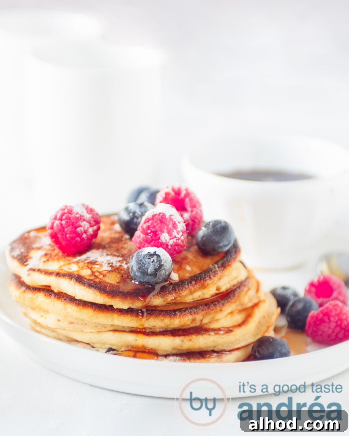 Cloud-Like American Pancakes 5 A stack of pancakes on a white plate with fresh fruit