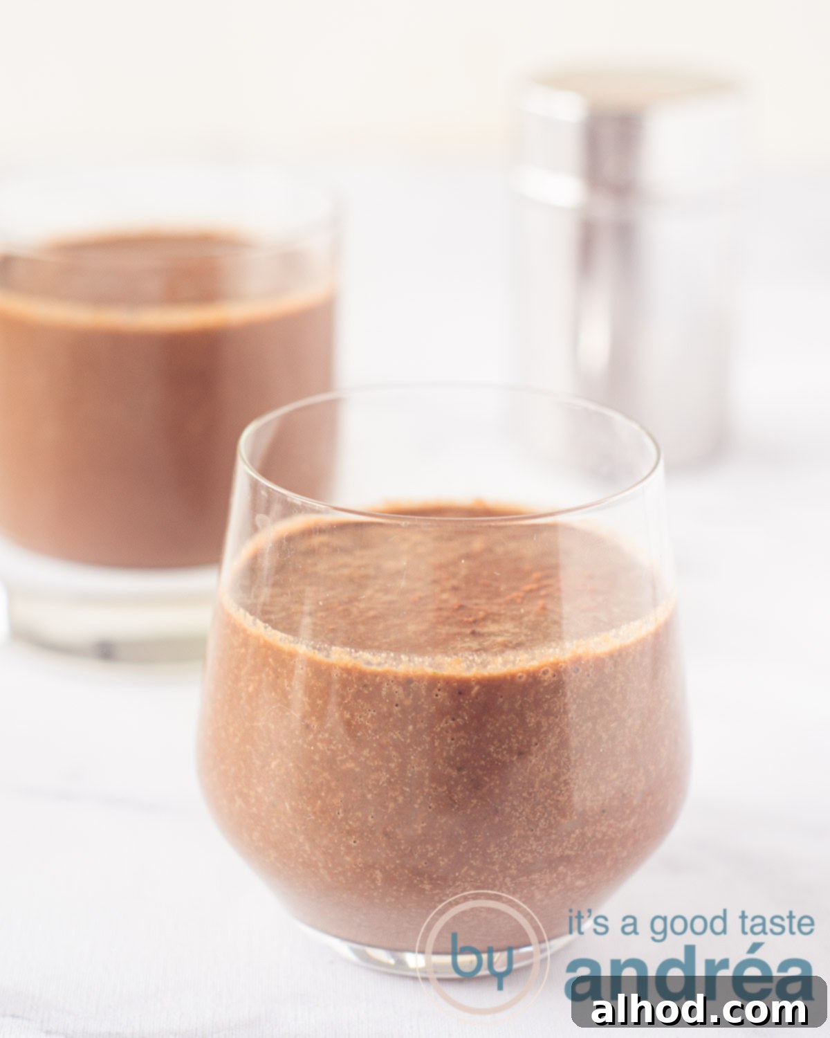 Cocoa Coconut Water Refresher 5 Two glasses filled with a chocolate coconut water smoothie on a white background. In the back a cocoa can.