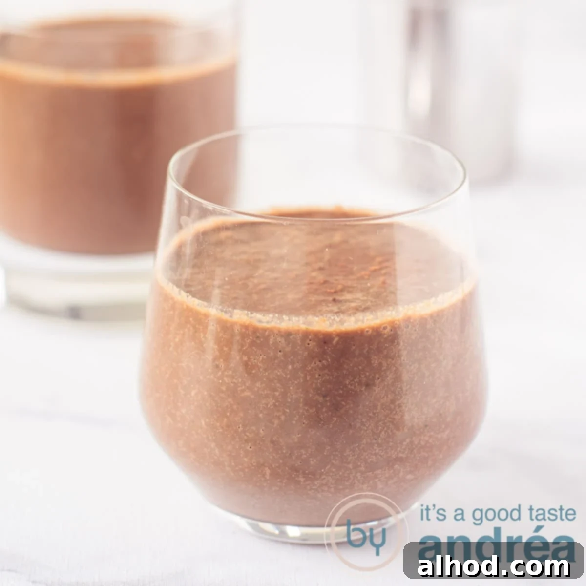 Cocoa Coconut Water Refresher 6 A square photo with two glasses filled with a smoothie with coconut water, cocoa, cherries and spinach. On a white background