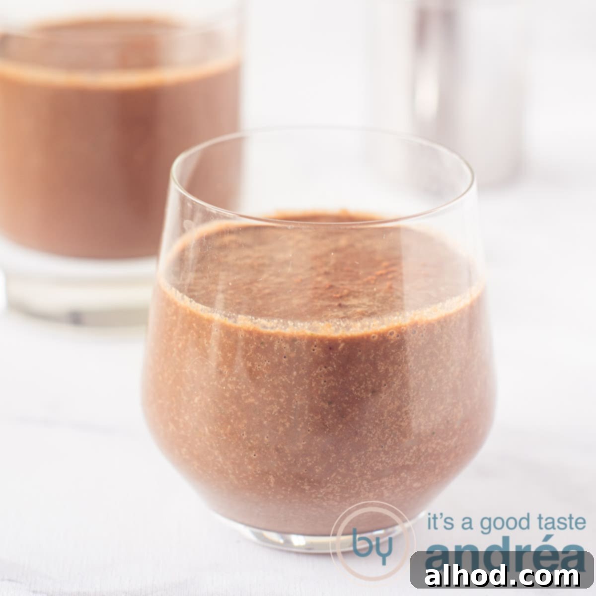6 Coconut Smoothie Recipes 3 Two glasses filled with a vibrant smoothie made with coconut water, cocoa, cherries, and spinach, presented on a white background.