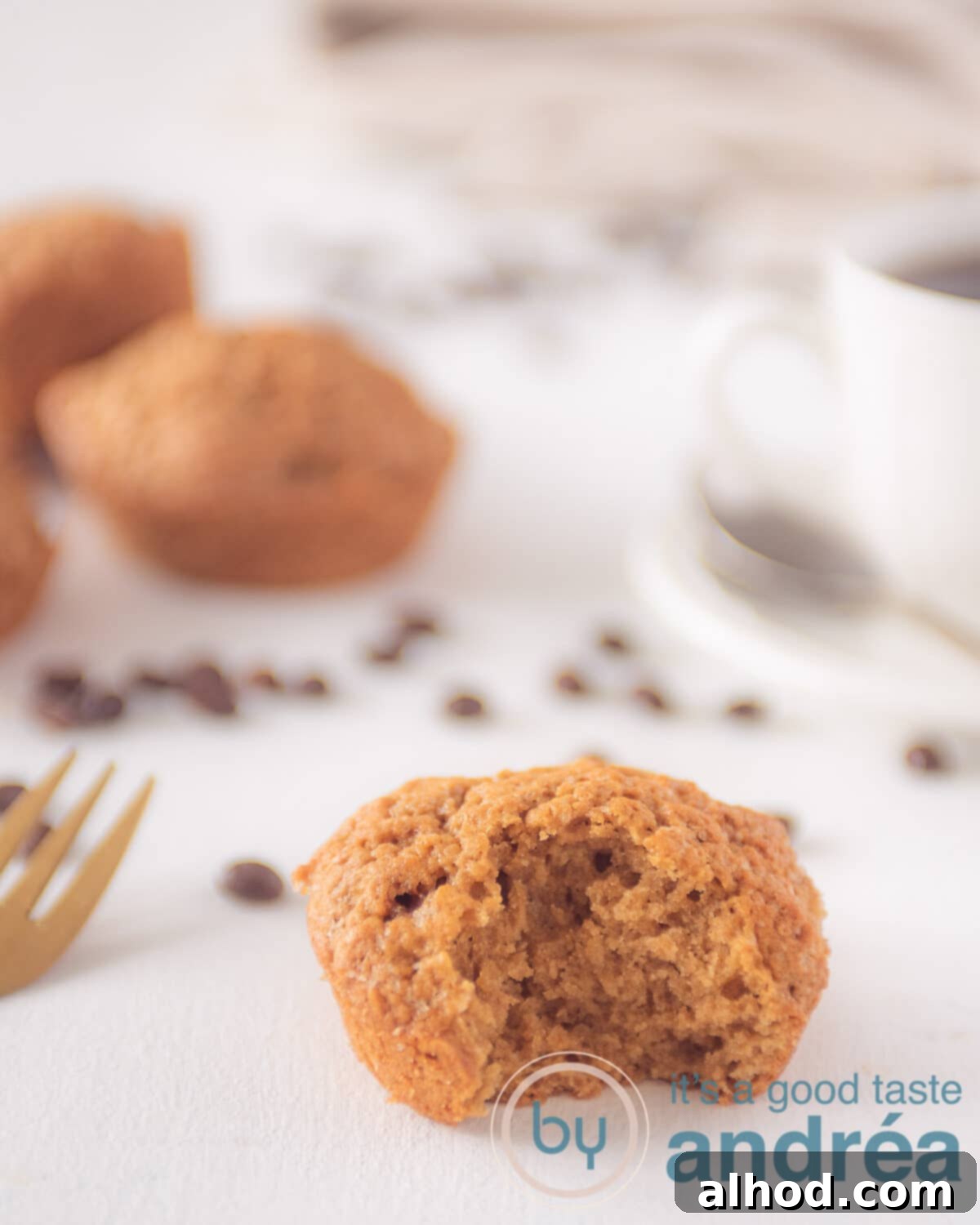 Espresso Muffins Recipe 2 A muffin with a bite out of it. Some muffins in the background. Coffee beans scattered around.