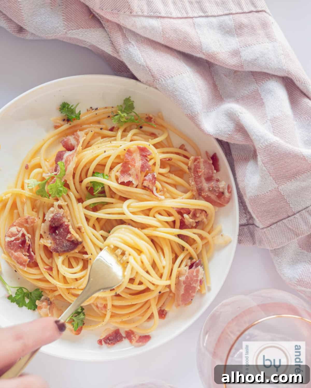 Authentic Spaghetti Carbonara The Cream Free Way 2 A photo taken from above from a white plate with spaghetti carbonara with Pancetta and eggs. No cream used. The pasta is beautifully coated in a golden, creamy sauce with crispy pieces of Pancetta visible.