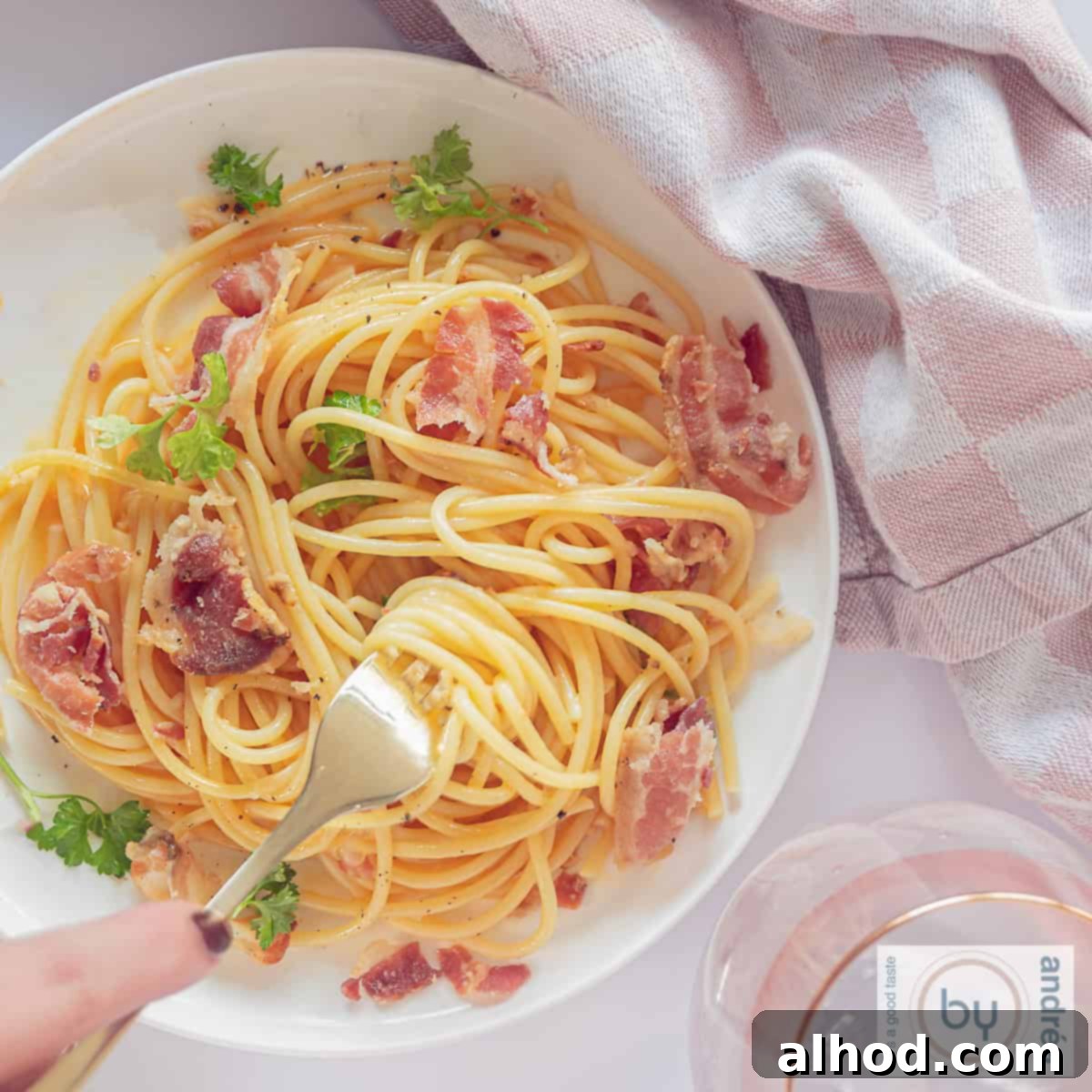Authentic Spaghetti Carbonara The Cream Free Way 3 A square picture taken from above from a white plate with no cream pasta carbonara. A fork pricks in the spaghetti, revealing the creamy sauce and crispy pancetta.