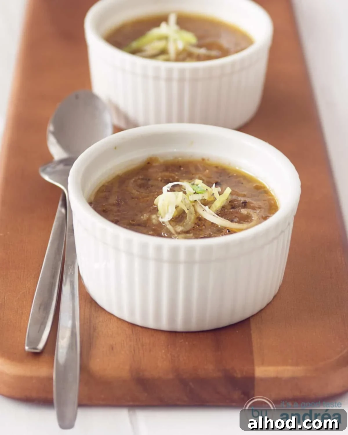 Hearty Vegetarian Cabbage Leek Soup 2 Two bowls on a wooden board filled with cabbage leek soup. Two spoons next to it.