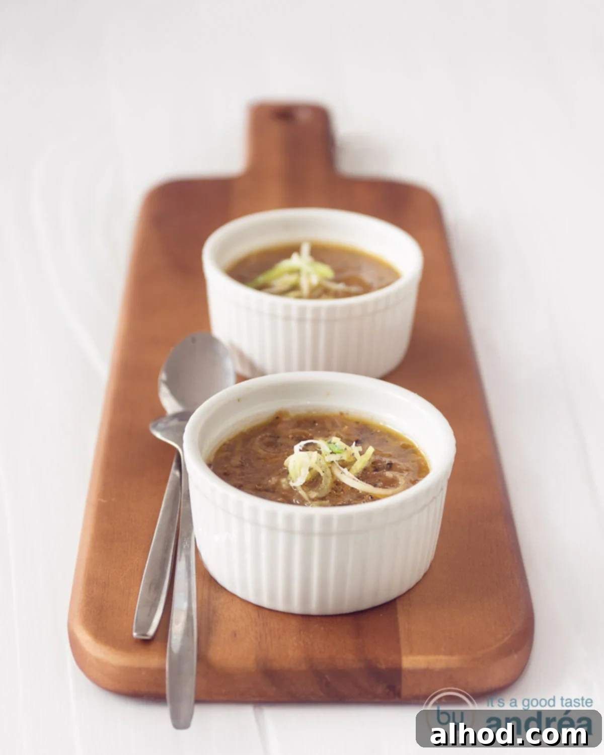 Hearty Vegetarian Cabbage Leek Soup 4 Two white bowls with vegetarian leek cabbage soup on a wooden board. A white background