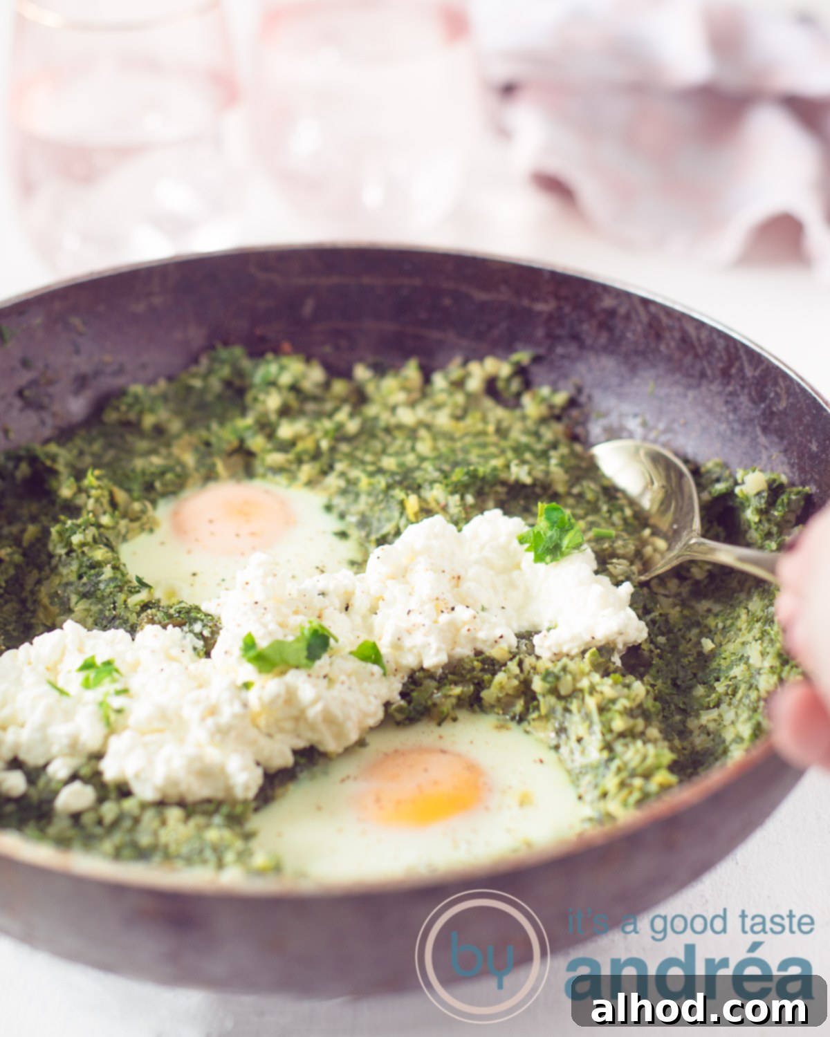 Velvety Cauliflower Rice with Spring Greens 5 A close-up shot of a black wok generously filled with the creamy spinach, leek, and cauliflower rice dish, artfully topped with two perfectly poached eggs and a swirl of cottage cheese, all presented on a clean white background. A spoon is poised, ready to take a delightful bite.