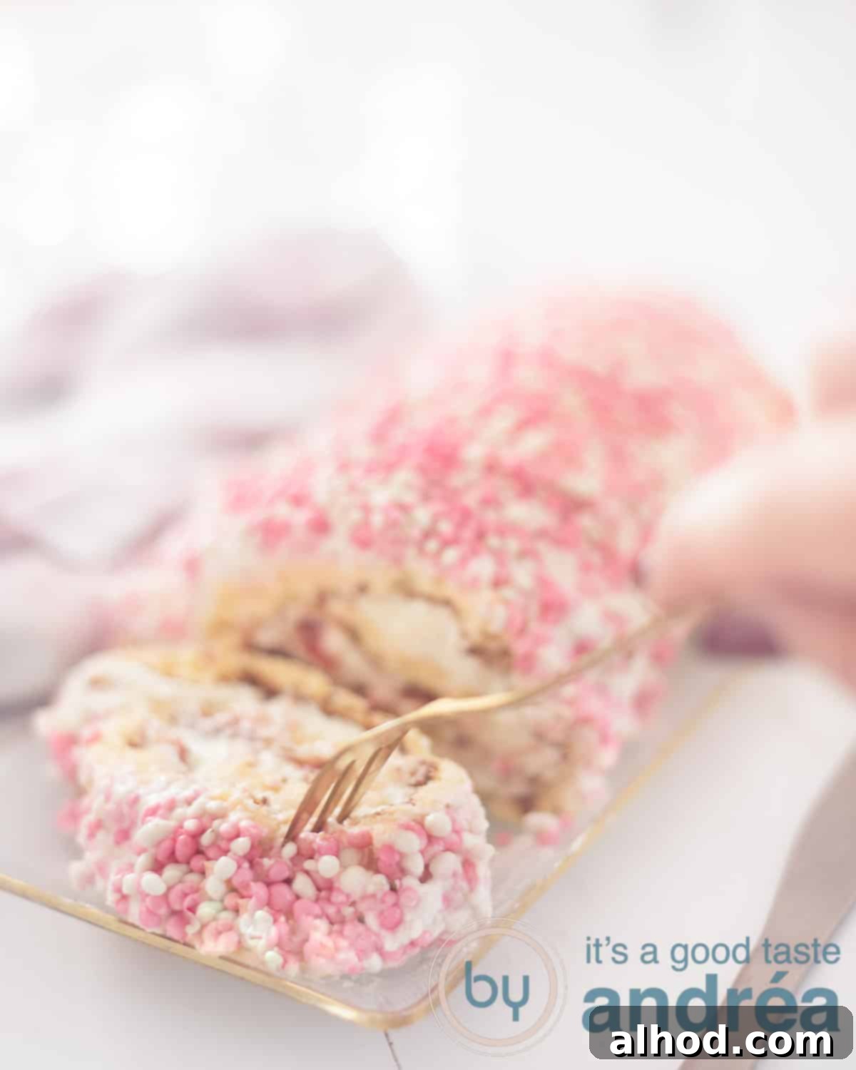 Baby Shower Swiss Roll 2 A beautifully sliced Baby Shower Cake Roll on a white background, revealing layers of cake, strawberry jam, and whipped cream, with a golden fork taking a bite. Perfect for a baby shower celebration.
