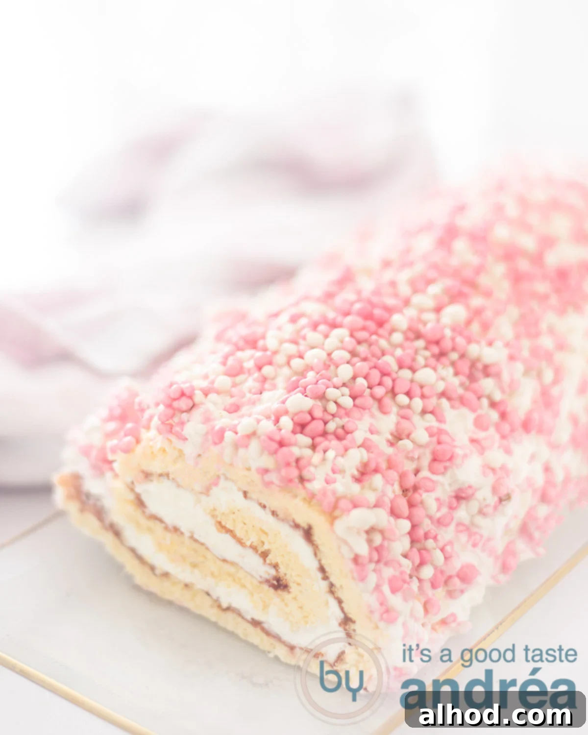 Baby Shower Swiss Roll 5 A close-up shot of a beautifully decorated baby shower cake roll, covered in white whipped cream and colorful sprinkles, ready to be served.