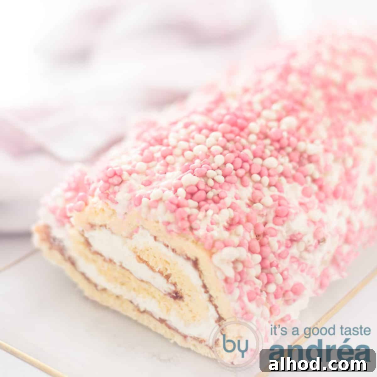 Baby Shower Swiss Roll 6 A square photo with part of a baby shower cake roll on a glass plate, garnished with sprinkles.