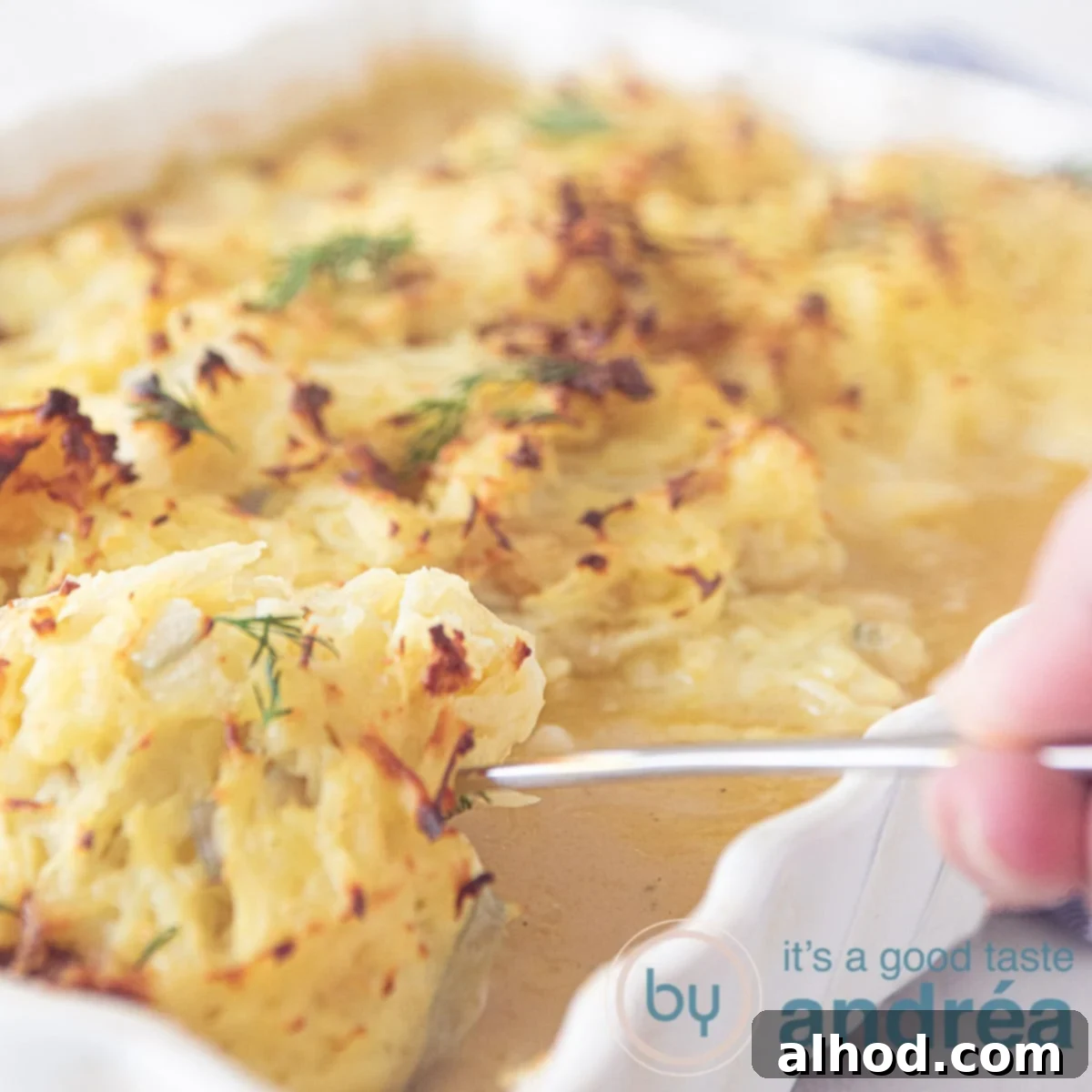 Hearty Cod and Potato Bake 6 a square photo of a white casserole taking out a cod fillet with Rösti topping