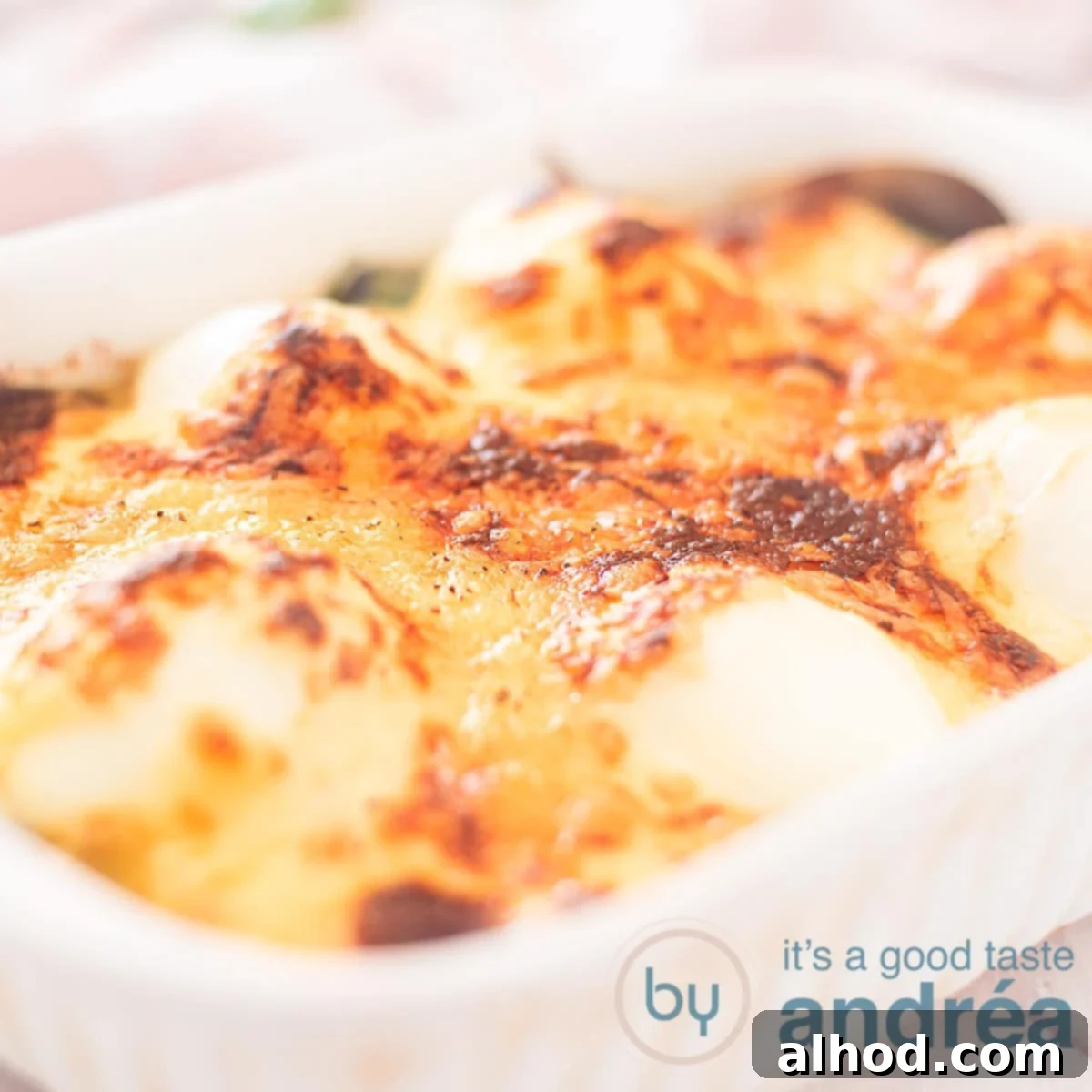 Classic Eggs Florentine 4 A square photo showing a white baking dish filled with egg au gratin on a bed of spinach.