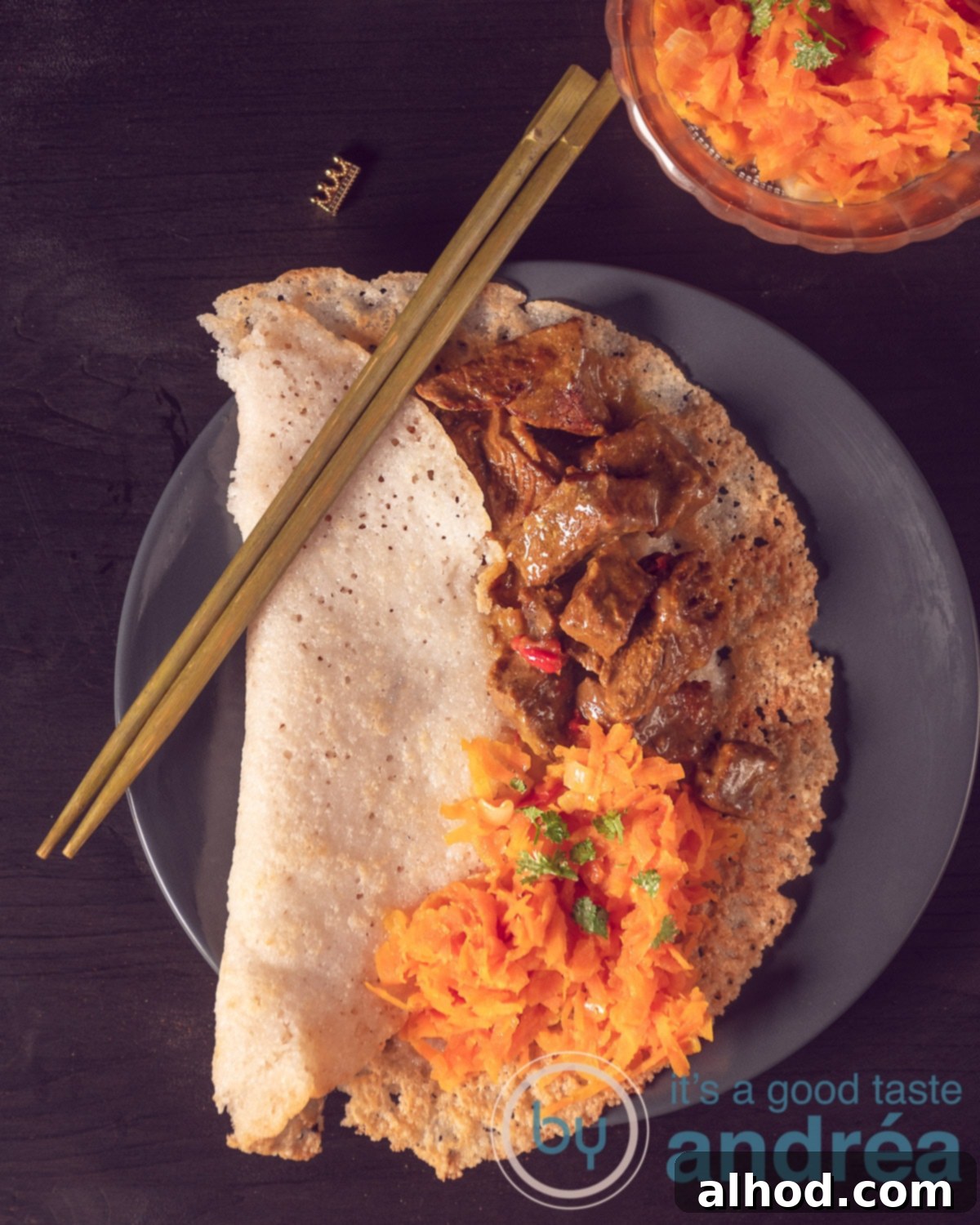 Lacy Sri Lankan Hoppers with Rich Beef Curry 9 A photo taken from above of a stuffed appam with beef curry, tropical carrots, two golden chopsticks and a gray plate on a black background