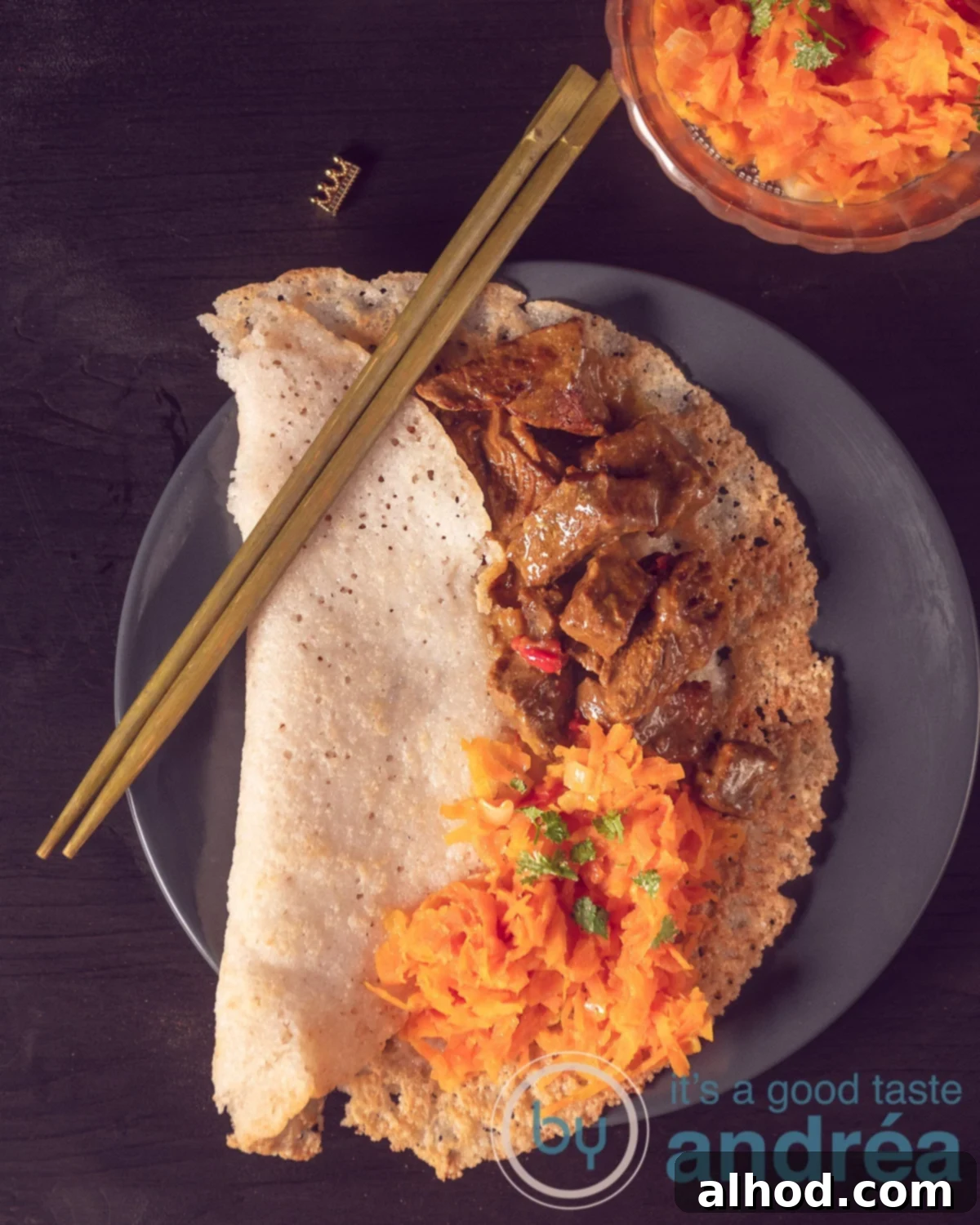 Hoppers & Heat: Sri Lanka's Spiced Beef Curry 9 A photo taken from above of a stuffed appam with beef curry, tropical carrots, two golden chopsticks and a gray plate on a black background, a complete Sri Lankan meal