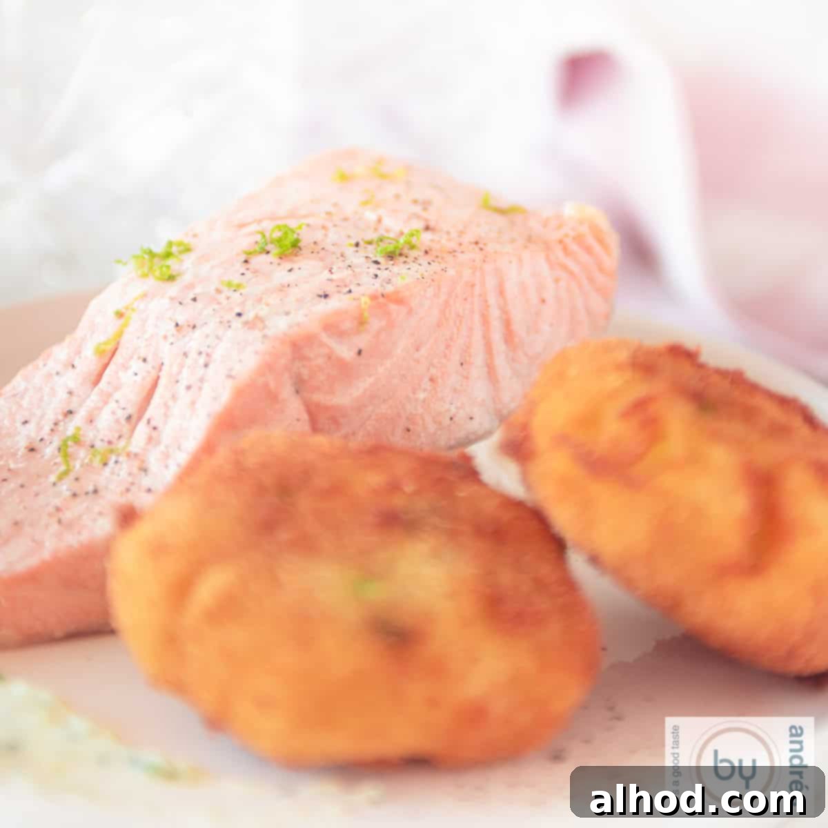 Wasabi-Spiked Smoked Salmon Latkes 6 A square photo with two wasabi potato croquettes and smoked salmon, warm, marinated on a white plate, ready to be served.