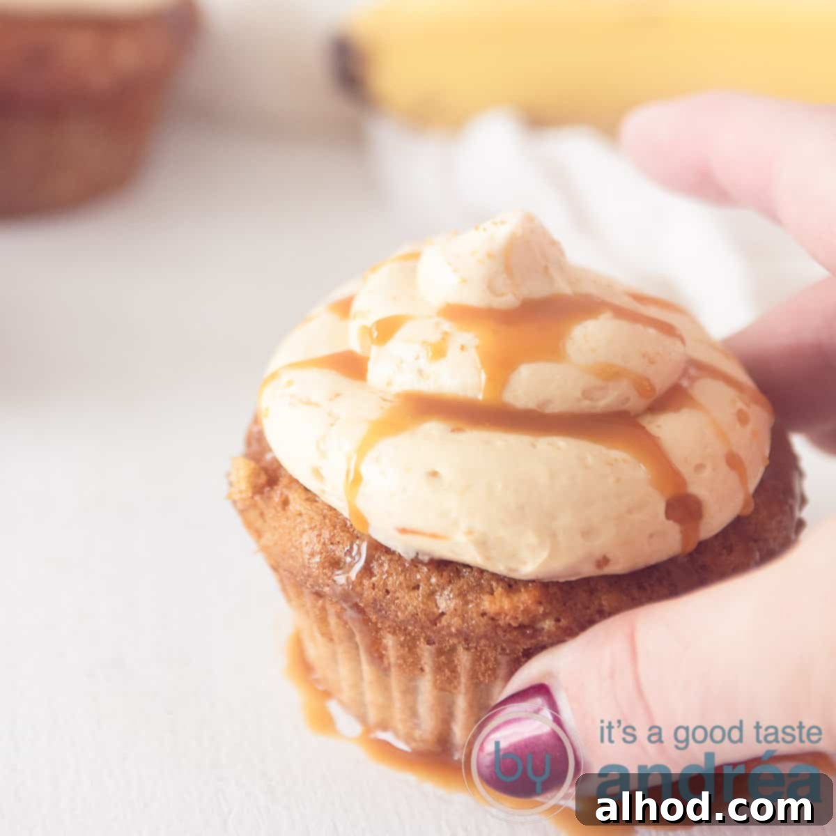A square photo with a cupcake with caramel cream and caramel sauce. A hand takes the cupcake