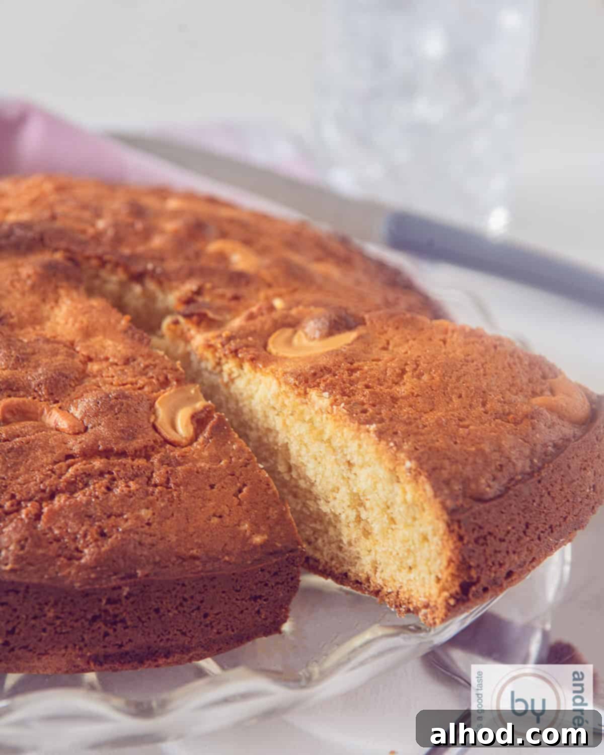 Fragrant Homemade Mawa Cake with Cardamom 2 A perfectly baked slice of an Indian Mawa Cake with a point cut out, showcasing its soft interior, cardamom speckles, and cashew topping.