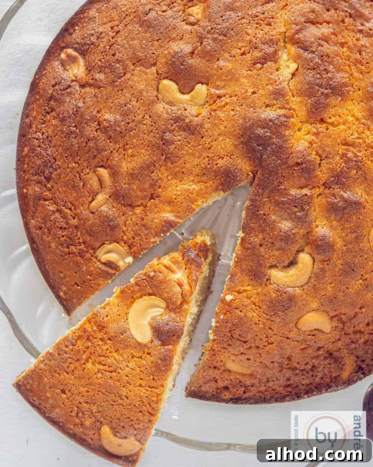 Fragrant Homemade Mawa Cake with Cardamom 3 A top-down view of a slice of an Indian Mawa cake, rich with cardamom and crunchy cashew nuts, with a piece removed.