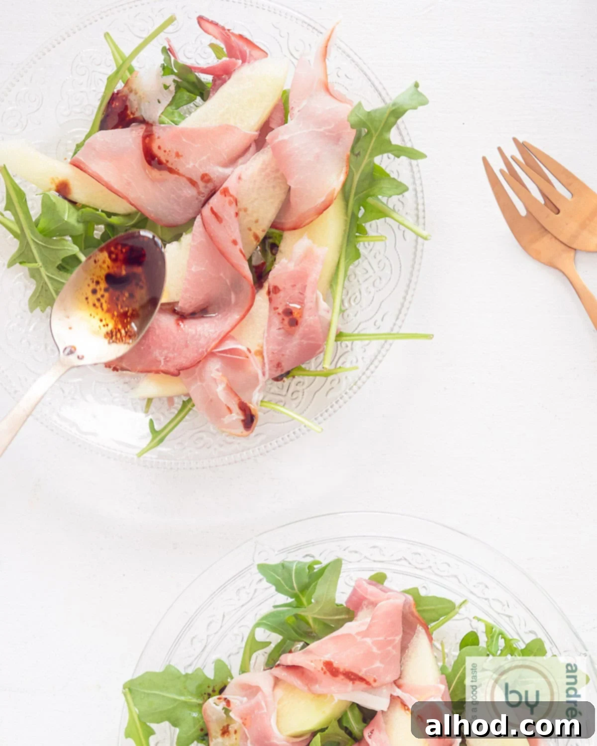 Summer Melon and Parma Ham Delight 3 Top-down view of an Italian Summer Salad featuring vibrant Galia melon, delicate Parma ham (prosciutto), and fresh arugula on a glass plate.