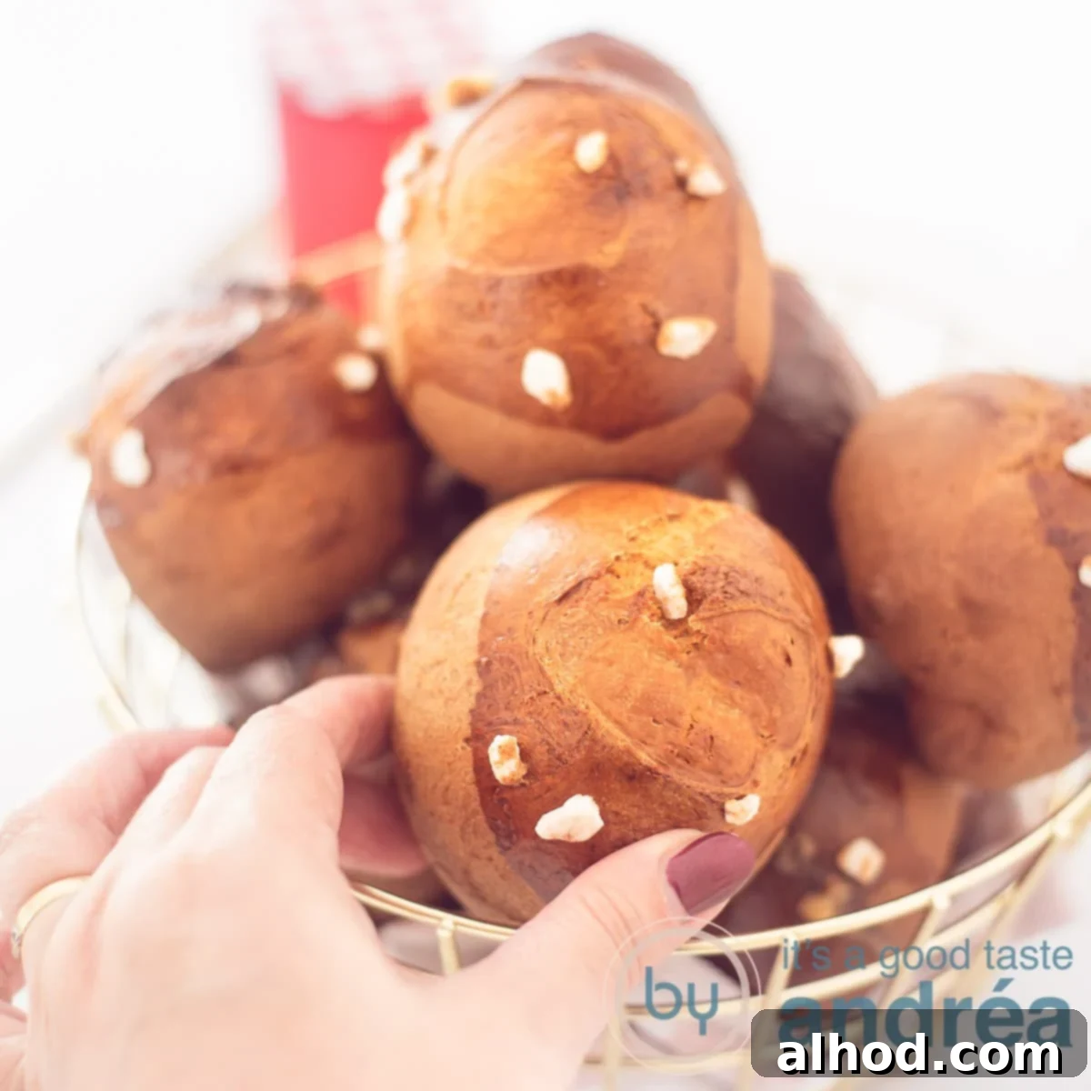 Dutch Pearl Sugar Buns 6 A square photo with a basket full of sugar balls with pearl sugar on a white background. A hand grabs a sandwich