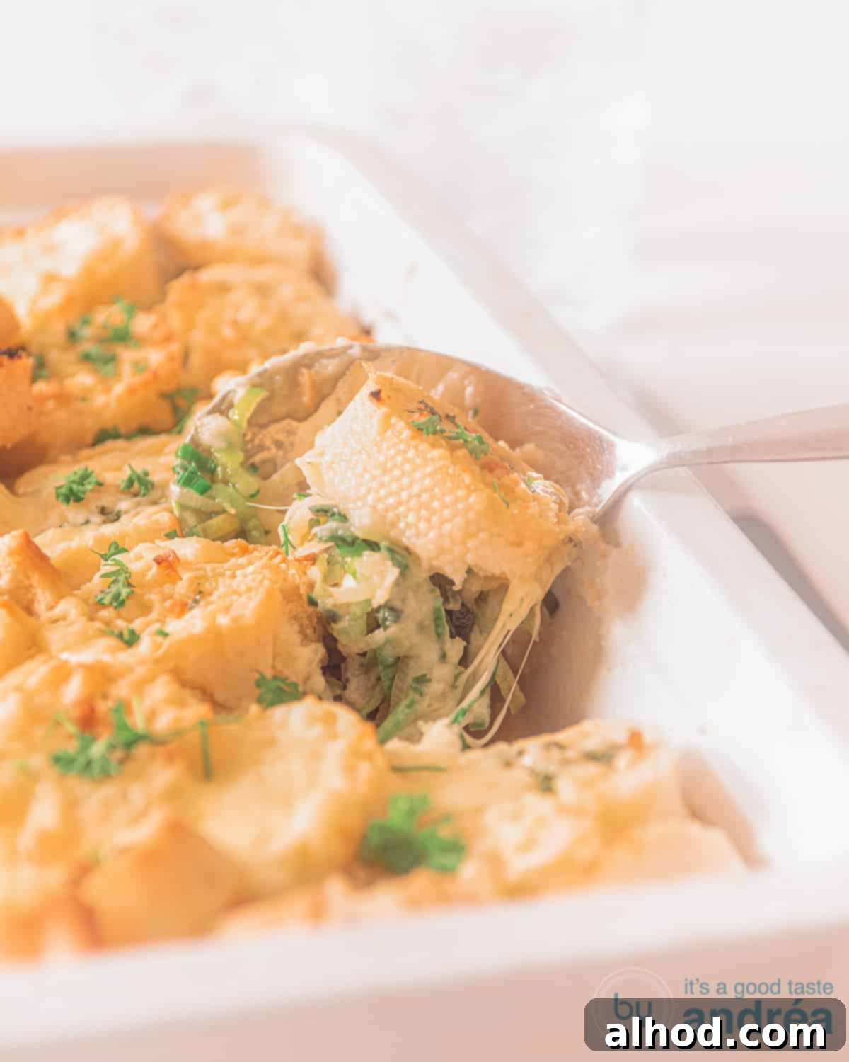 Creamy Chicken and Leek Comfort Bake 4 Leek chicken casserole in a white dish. A spoon inside the oven dish.