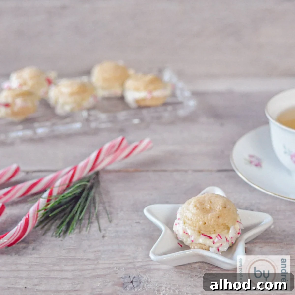 Holiday Macaron Magic 3 A square photo with a white Christmas bowl with a macaron. Candy canes and a glass bowl with additional macarons in the background