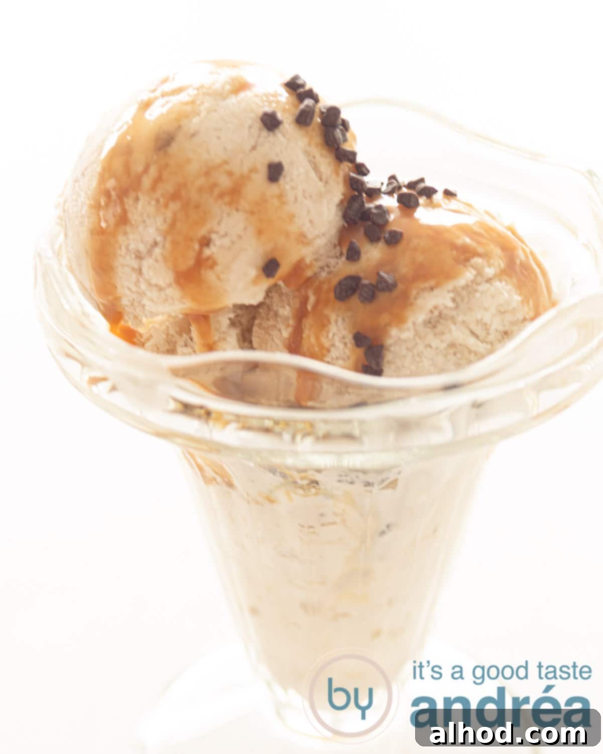 Velvety Homemade Banana Ice Cream 2 Homemade banana ice cream in a glass bowl, topped with chocolate sprinkles and caramel sauce, ready to be served.