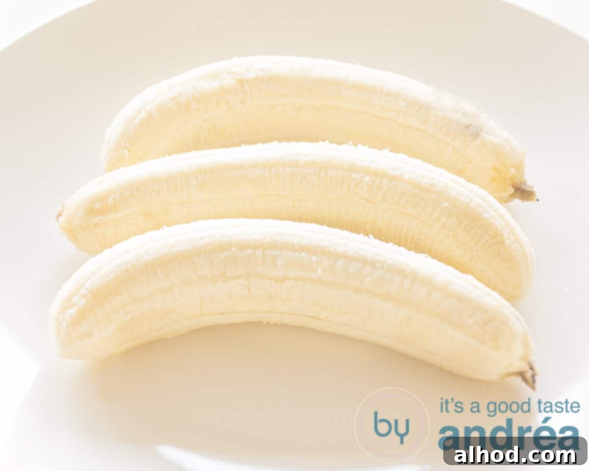 Velvety Homemade Banana Ice Cream 3 Three perfectly peeled ripe bananas on a clean white plate, ready for mashing.