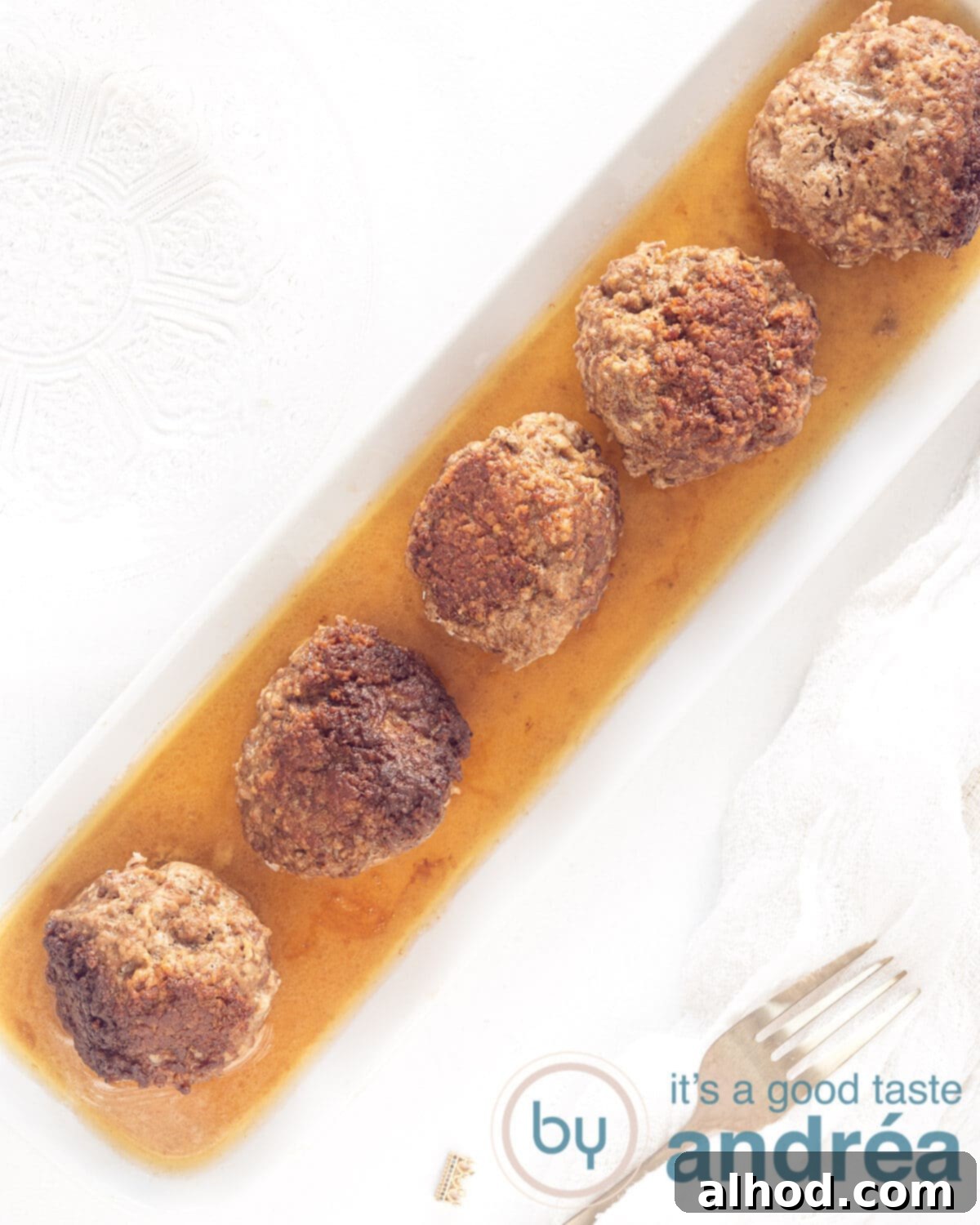 Granny's Traditional Dutch Meatballs 2 A white platter full of tender, juicy Dutch meatballs lying in the rich, savory gravy, ready to be served.