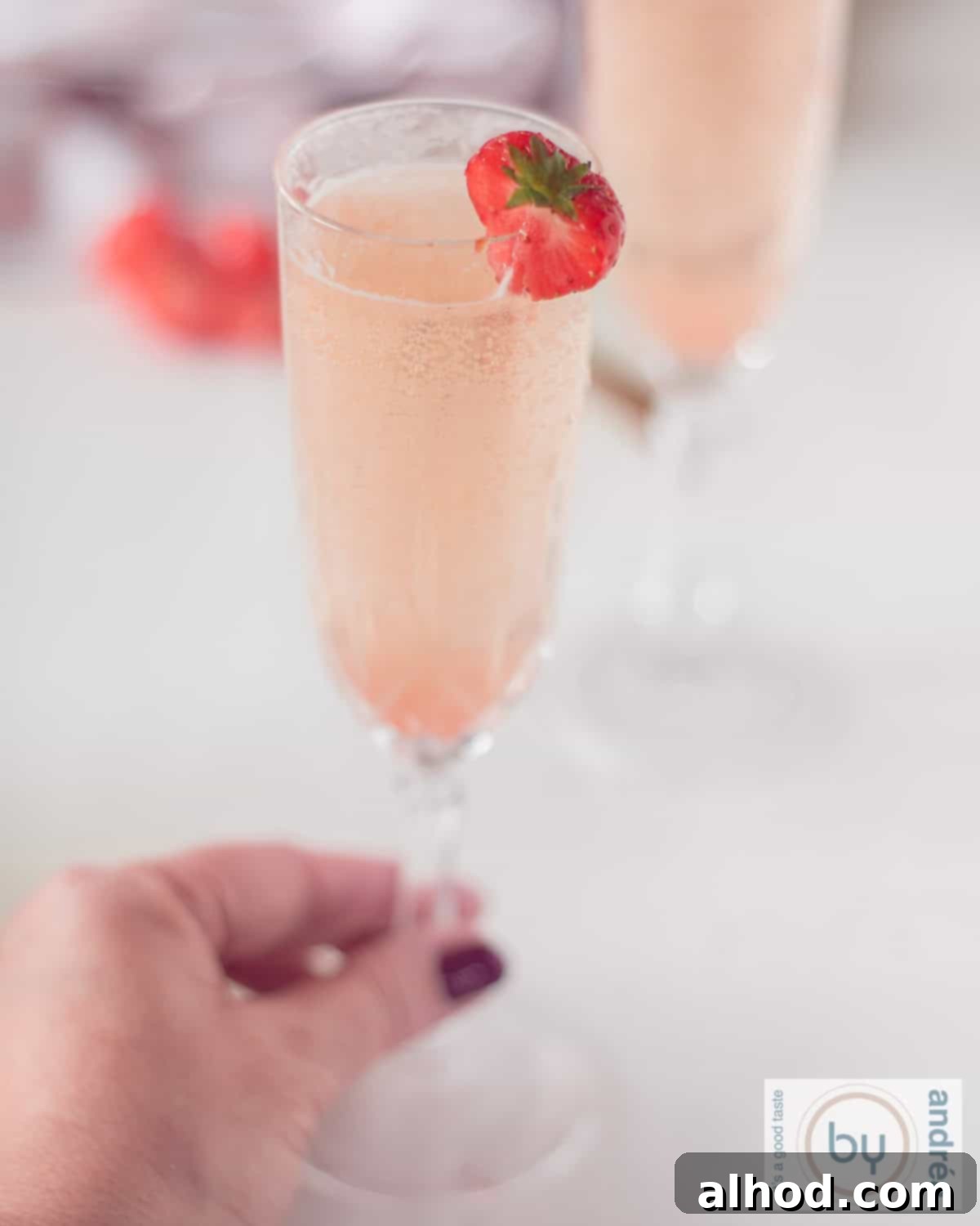 Bubbly Strawberry Bellini Delight 3 A height shot of a strawberry cocktail for Valentine's Day. A hand is holding the glass