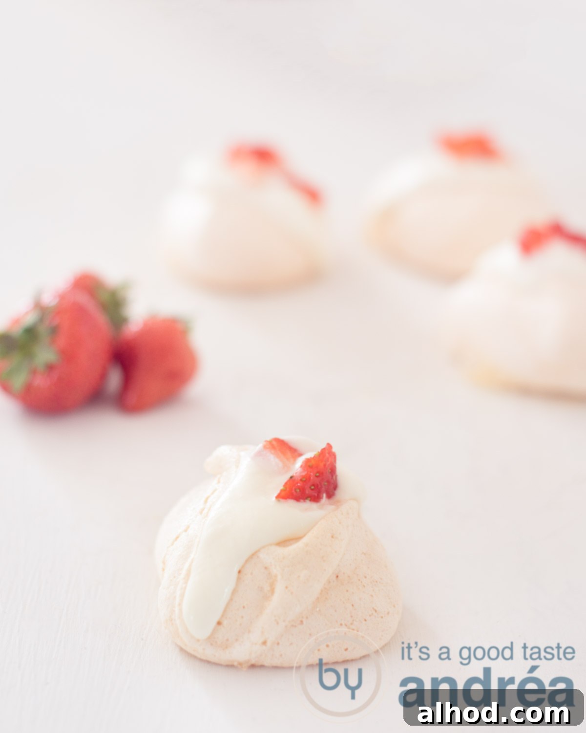 Fragrant Rose Meringue Kisses 5 Rose meringues with fresh strawberries and whipped cream, garnished with delicate rose petals, arranged on an elegant serving plate.