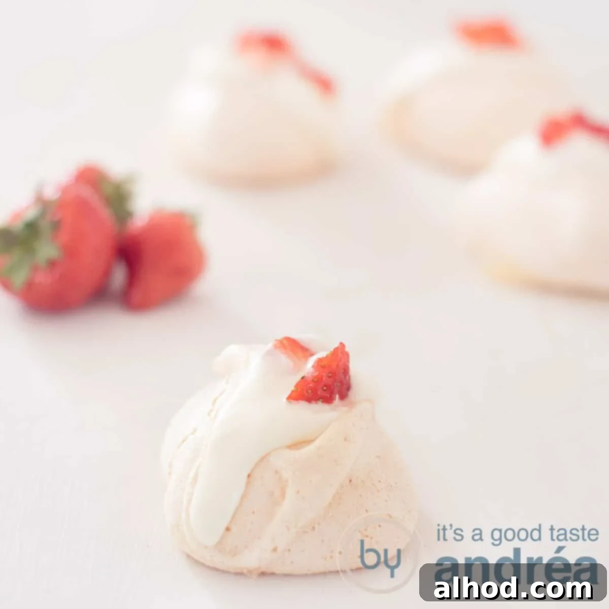 Fragrant Rose Meringue Kisses 6 A square photo with rose meringue in the foreground and three in the background. Left strawberries.