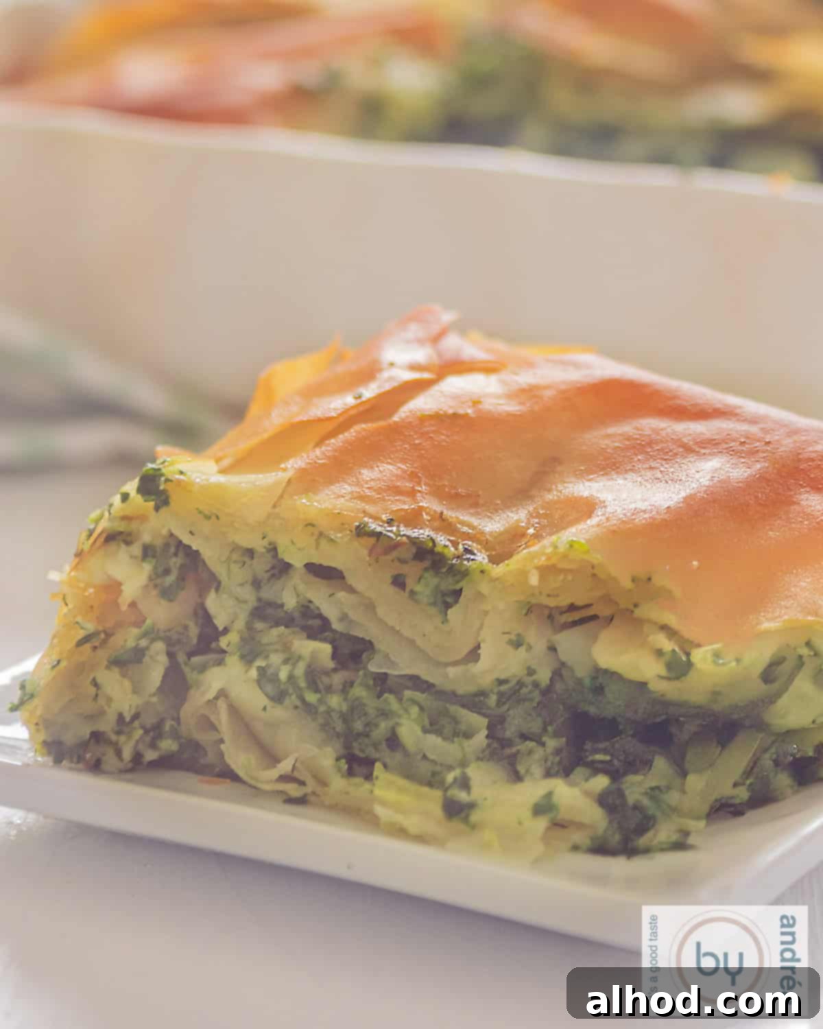 The Easiest Greek Spanakopita Spinach and Feta Pie 3 A macro shot of spanakopita, greek quiche on a white plate.