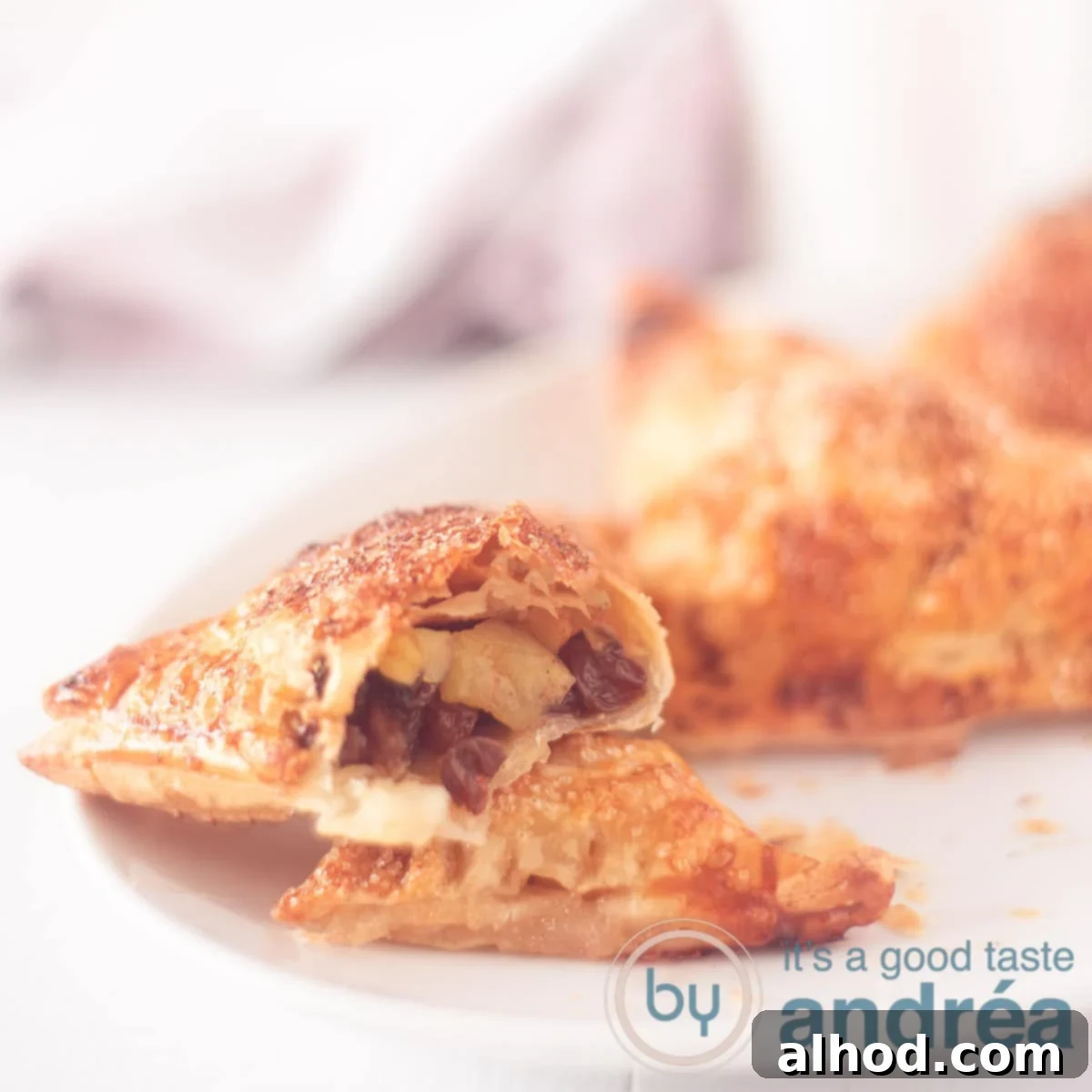 Classic Dutch Apple Turnovers 6 A square photo with an apple turnover cut open, showing the filling on a white background.