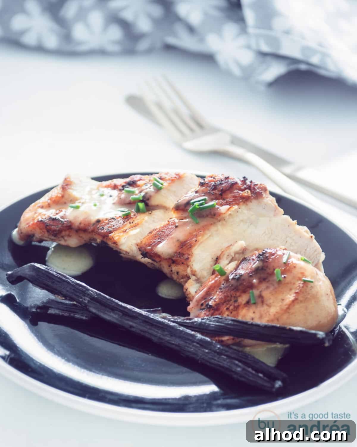Vanilla-Glazed Chicken 1 Chicken with vanilla sauce on a black plate, garnished with chives