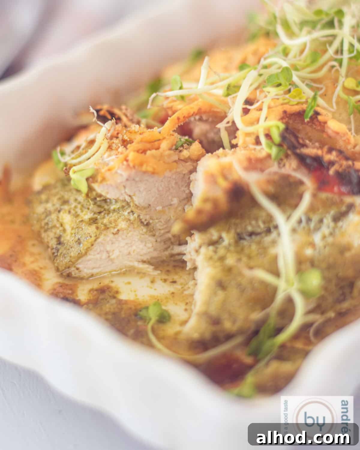 Golden Pesto Chicken with Sundried Tomatoes and Melty Mozzarella 2 A white oven dish with chicken fillet, cut open with pesto and cheese, ready to be served.