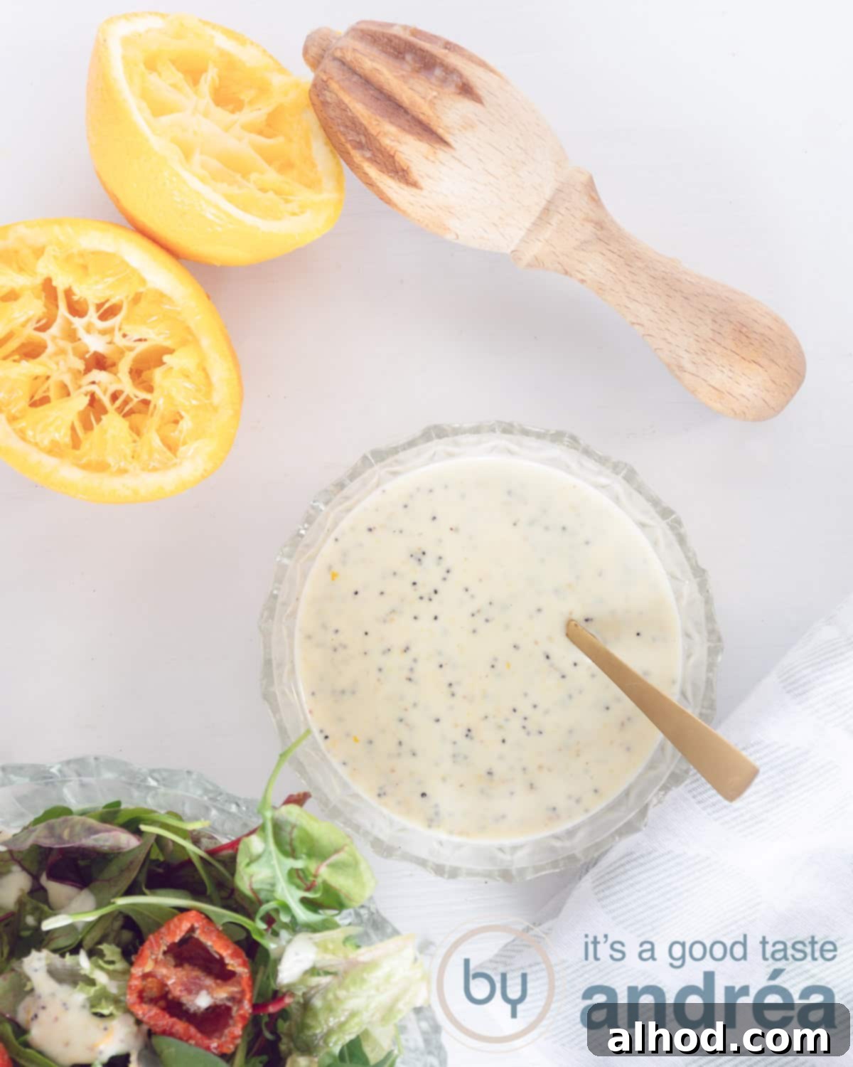 A photo from above with a bowl of honey-mustard dressing at the bottom right. Top left two half oranges and a press. Lins at the bottom of a green salad.