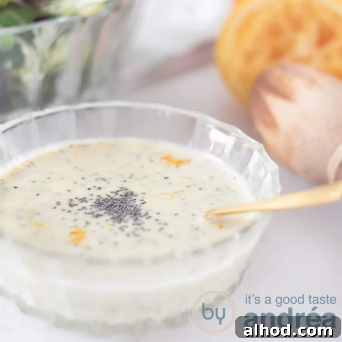 Velvety Orange Honey Mustard Sauce 6 A square photo with a bowl of Honey Mustard dressing with orange zest and poppy seeds. A white background. Top right a squeezed orange. Top left a green salad