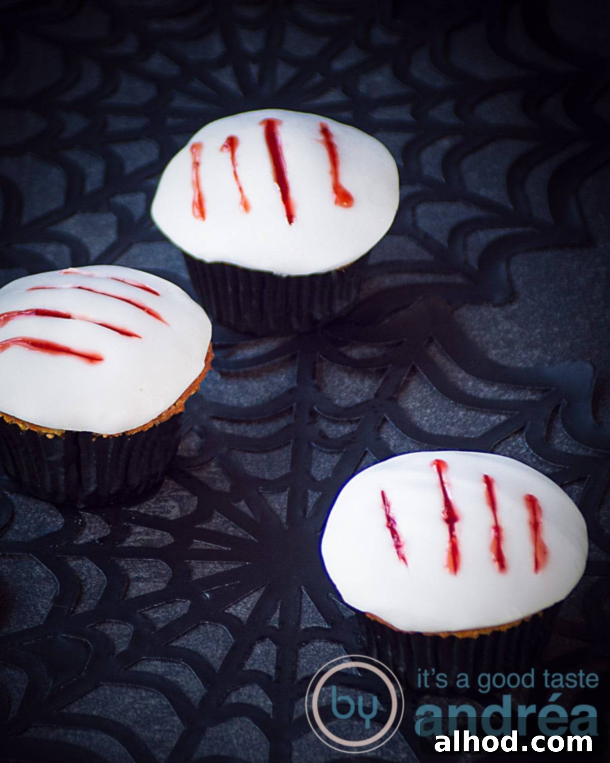 Howling Werewolf Claw Cupcakes 3 Close-up of three spooky Halloween Werewolf Claw Cupcakes featuring jagged claw marks filled with vibrant strawberry 'blood' on a backdrop of eerie cobwebs, perfect for a themed party.