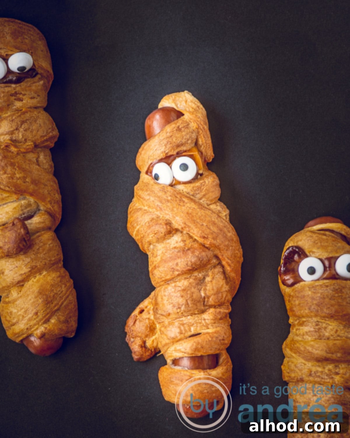 Halloween Hot Dog Mummies 2 One hot dog mummy and two partial mummies wrapped in dough, on a white background, ready for baking.