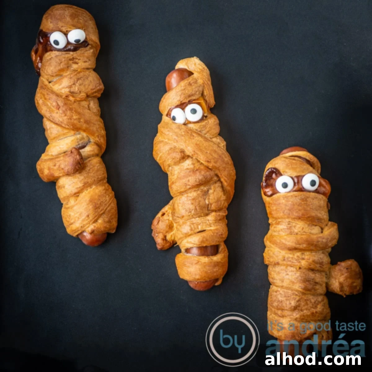 Halloween Hot Dog Mummies 4 A square photo with three frankfurter mummies in puff pastry on a black background for Halloween