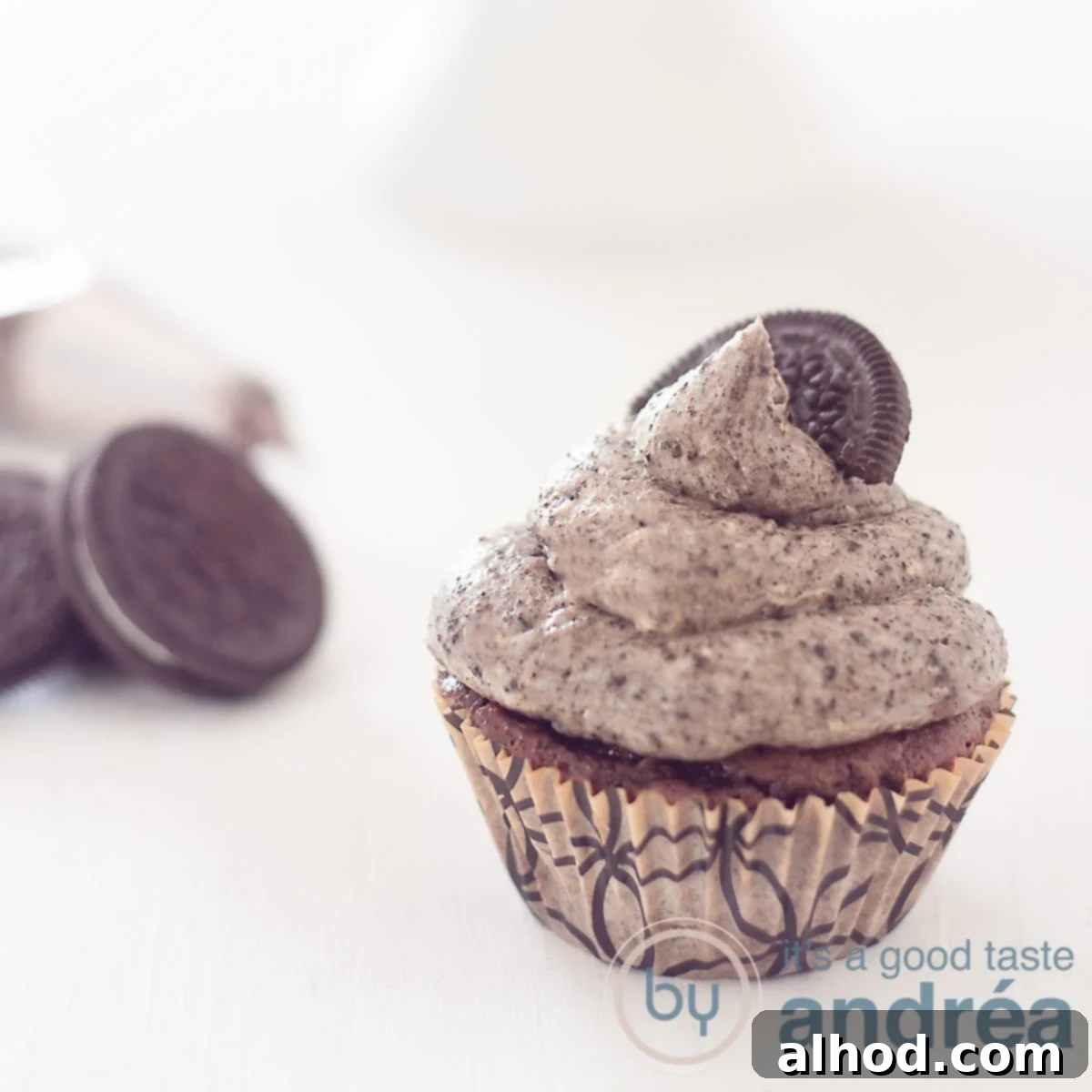 Simple and Scrumptious Oreo Chocolate Cupcakes 7 A square photo with an Oreo cupcake in the front right. Left behind Oreo cookies. A white background.