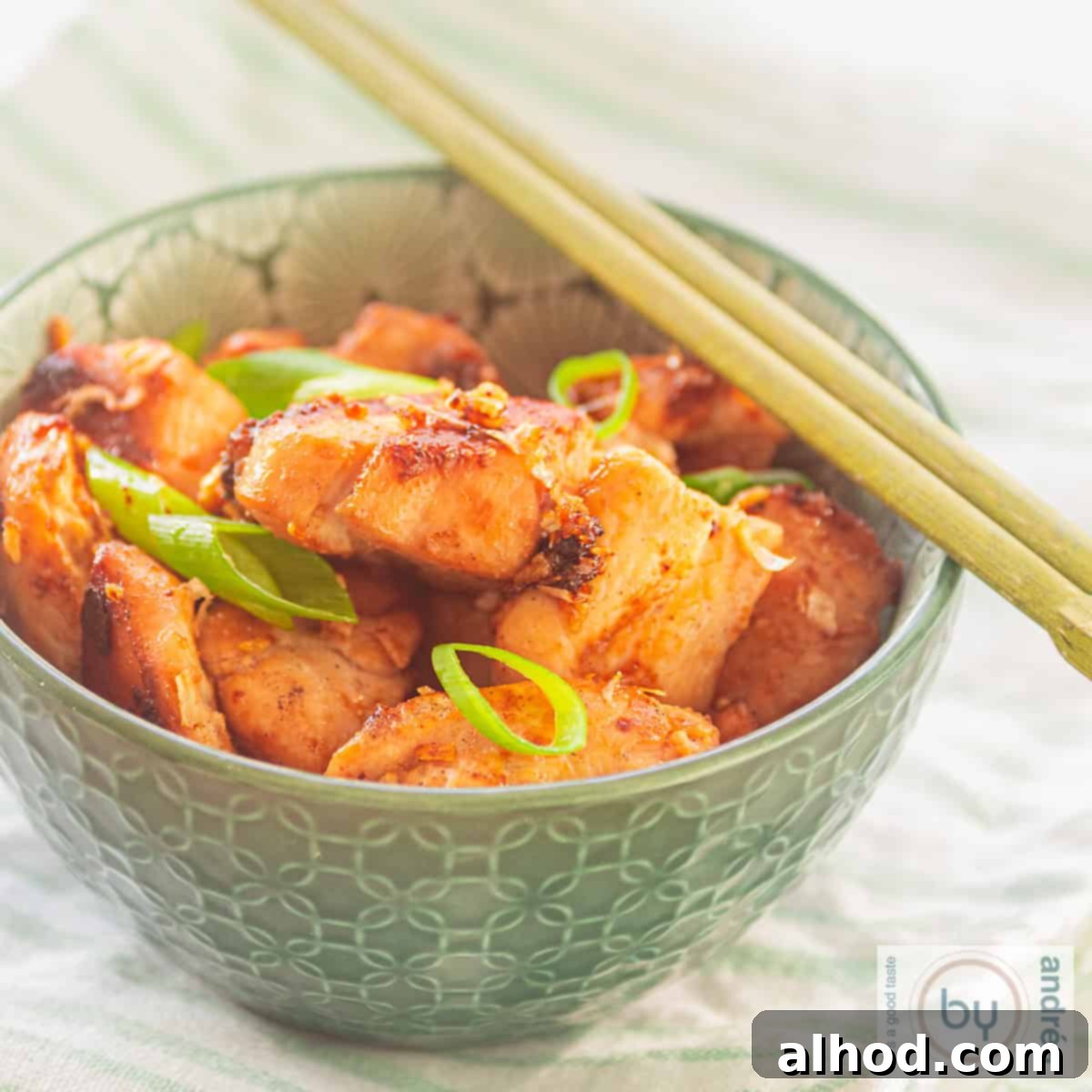 Whip Up Thai Chicken in 15 Minutes 4 A square photo of a green bowl containing a dish of chicken seasoned with four sauces, inspired by Thai cuisine.