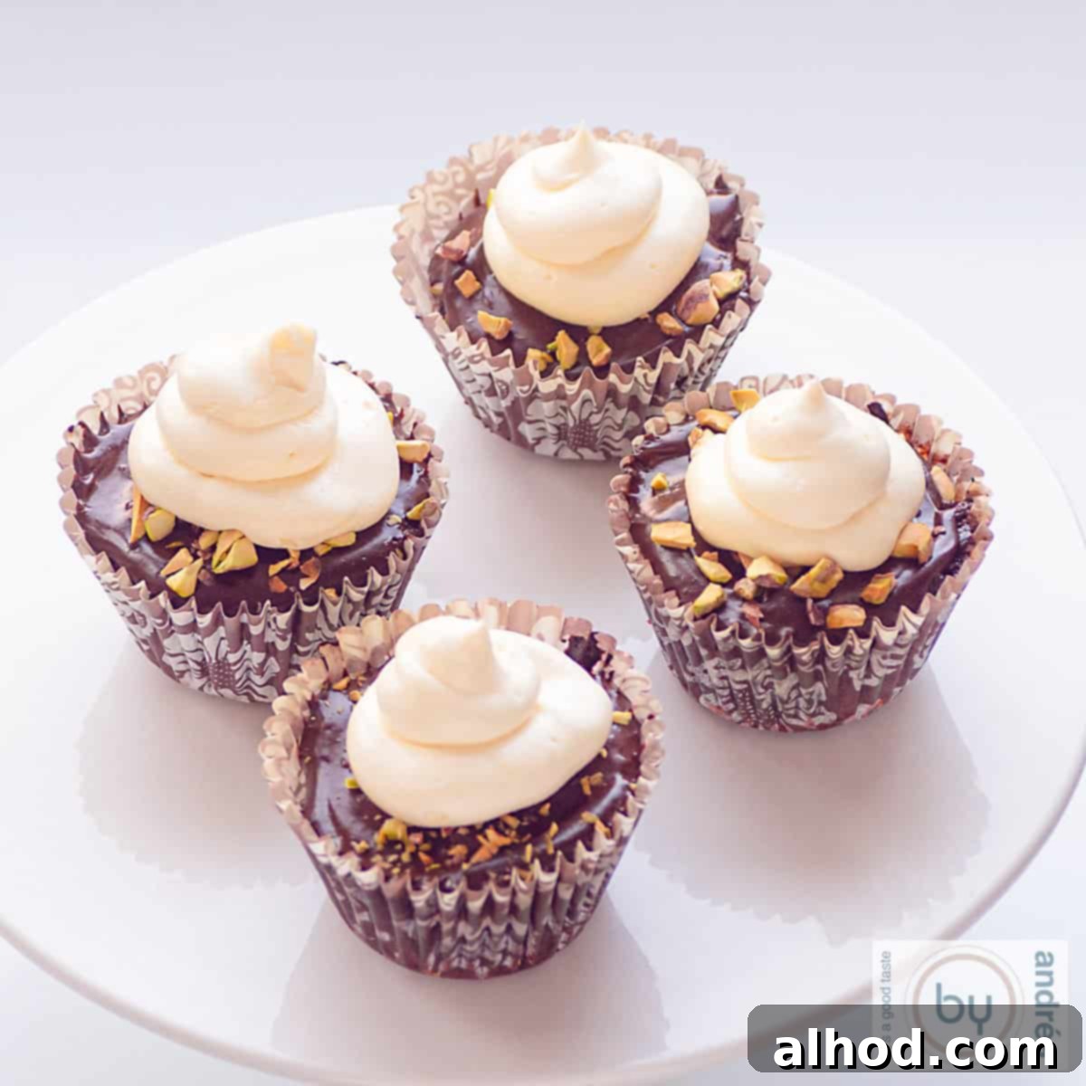 Decadent Triple Chocolate Cupcakes 10 A square picture of a pristine white cake stand holding four exquisite Triple Chocolate Cupcakes, each crowned with glossy ganache and fluffy white chocolate buttercream.