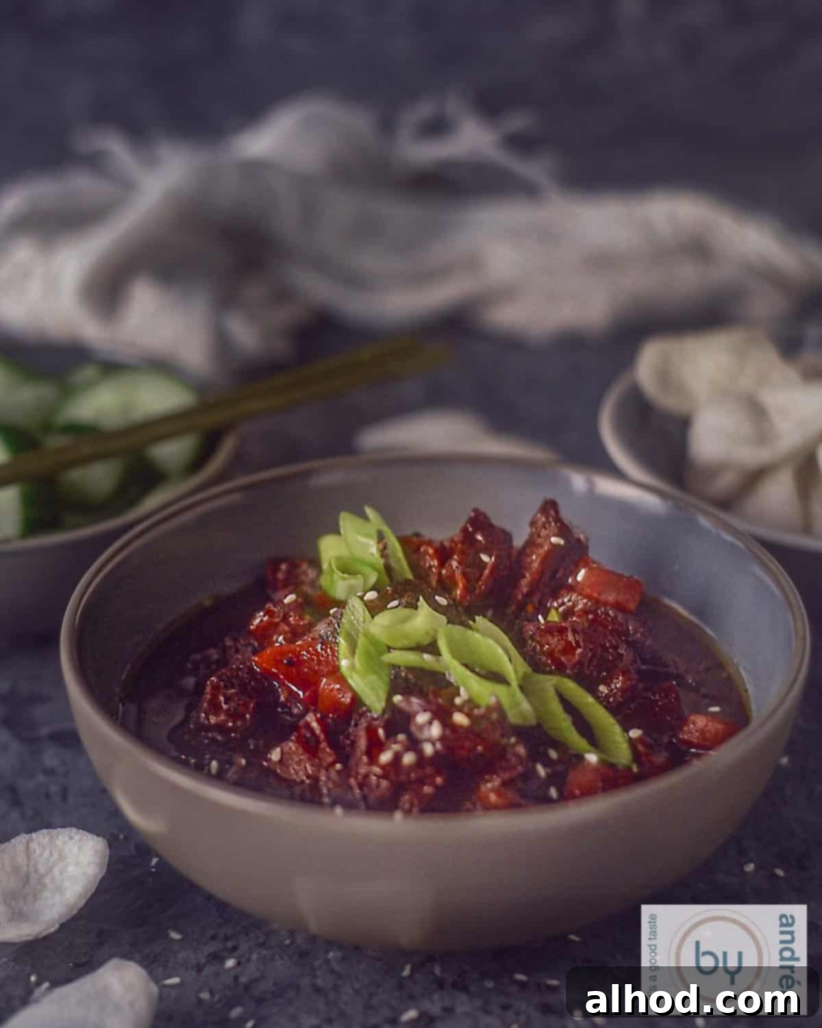 Easy Crockpot Mongolian Beef 2 A height photo of a grey bowl filled with slow cooked Mongolian beef with green onions garnish.