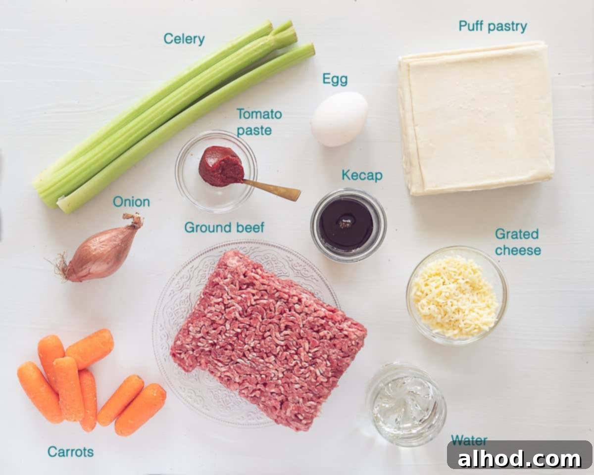Puff Pastry Beef Pot Pie 3 A beautiful arrangement of fresh ingredients for a homemade Beef Shepherd's Pie with Puff Pastry, including raw ground beef, thawed puff pastry sheets, vibrant carrots, crisp celery, a yellow onion, a tube of tomato paste, a bottle of Kecap Manis, a fresh egg, and shredded cheese, all individually labeled on a clean white background.