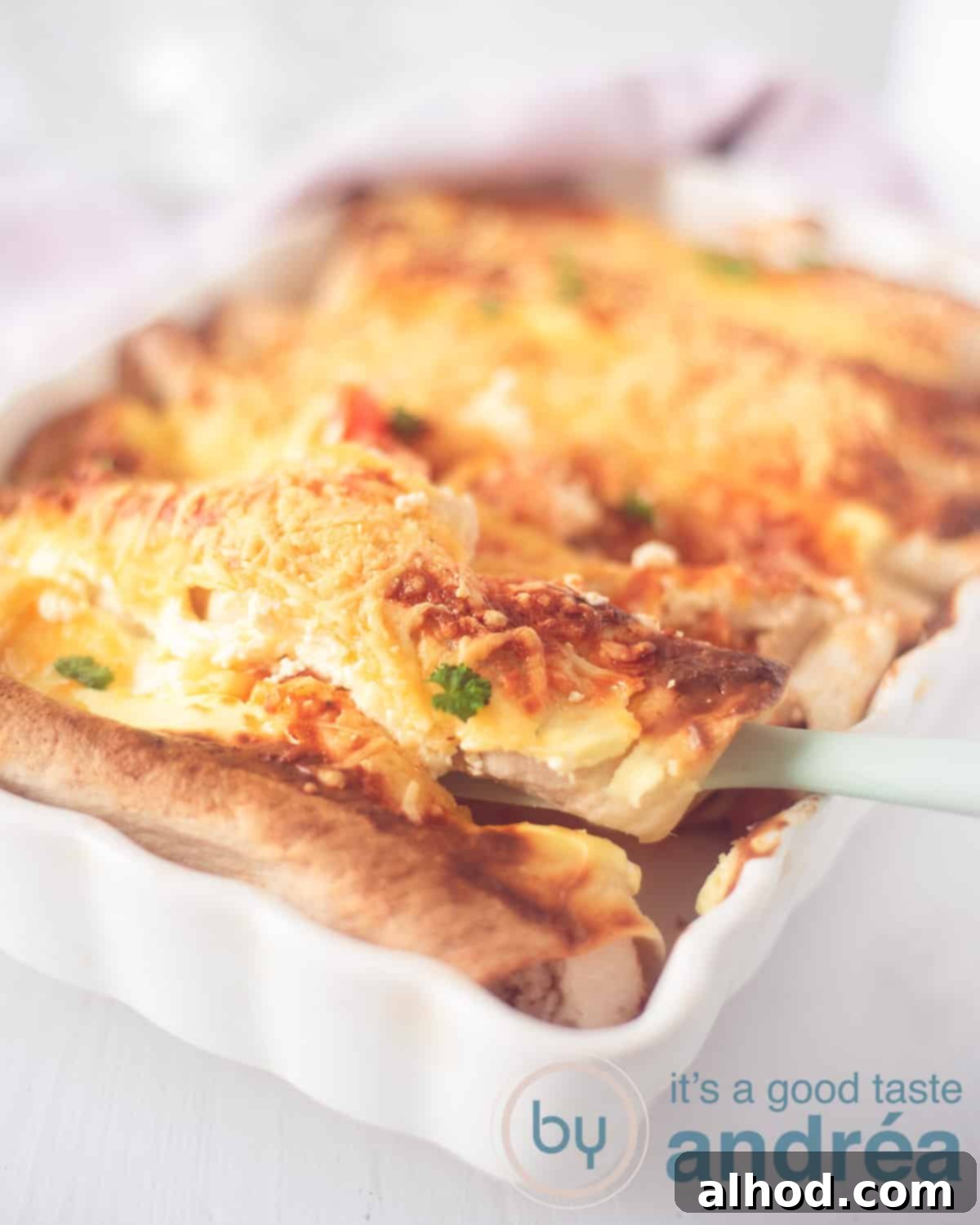 Ultimate Chicken Enchiladas 2 A vibrant, close-up photo of a baking dish filled with golden-brown chicken enchiladas, perfectly gratinated with crispy cheese. A spatula is scooping out a wrap, revealing the creamy filling. In the soft-focus background, a charming pink and white tea towel adds a touch of warmth.