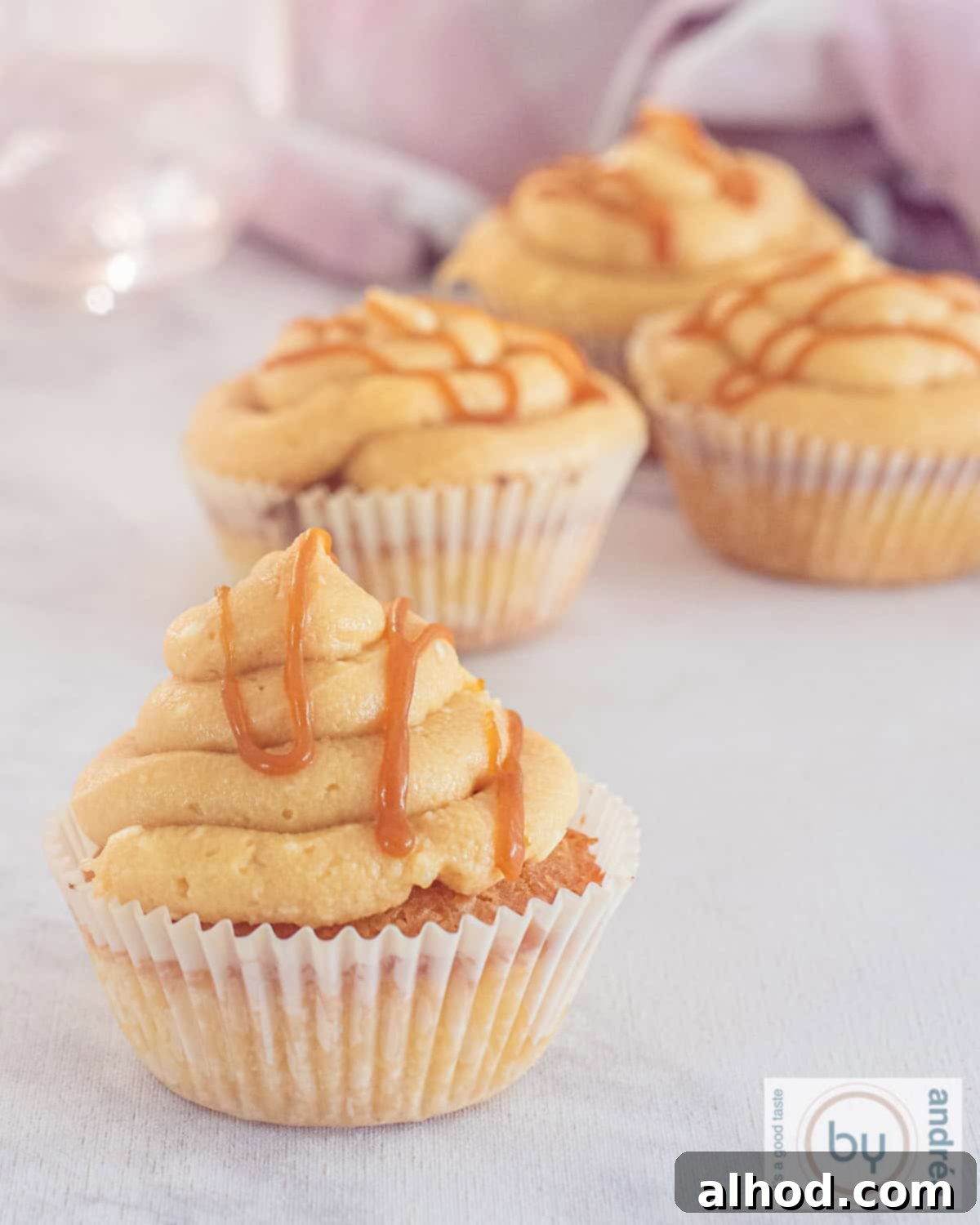 Effortless Salted Caramel Cupcake Delights 2 A height picture with four caramel cupcakes with frosting and salted caramel.