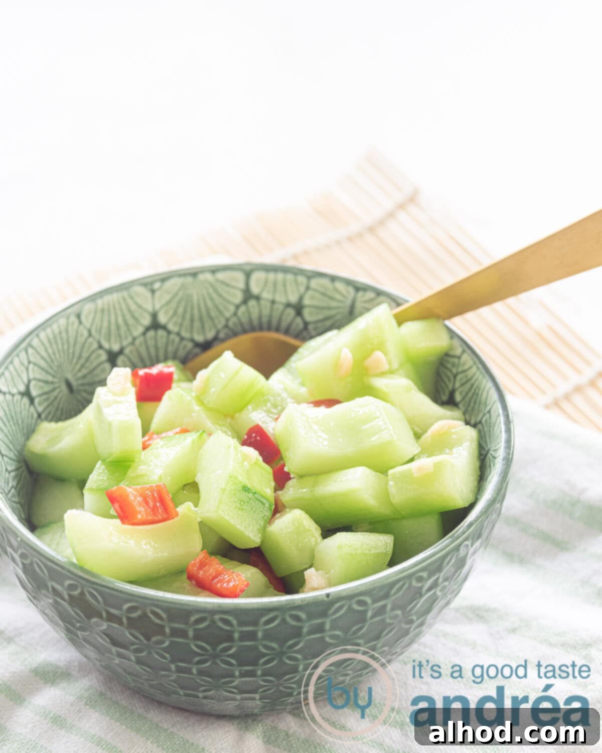 Spicy Garlic Cucumber Crunch 2 A vibrant green bowl filled with finely cut sweet and sour cucumber salad, garnished with fresh red pepper strips and minced garlic, ready to serve as a refreshing side dish.
