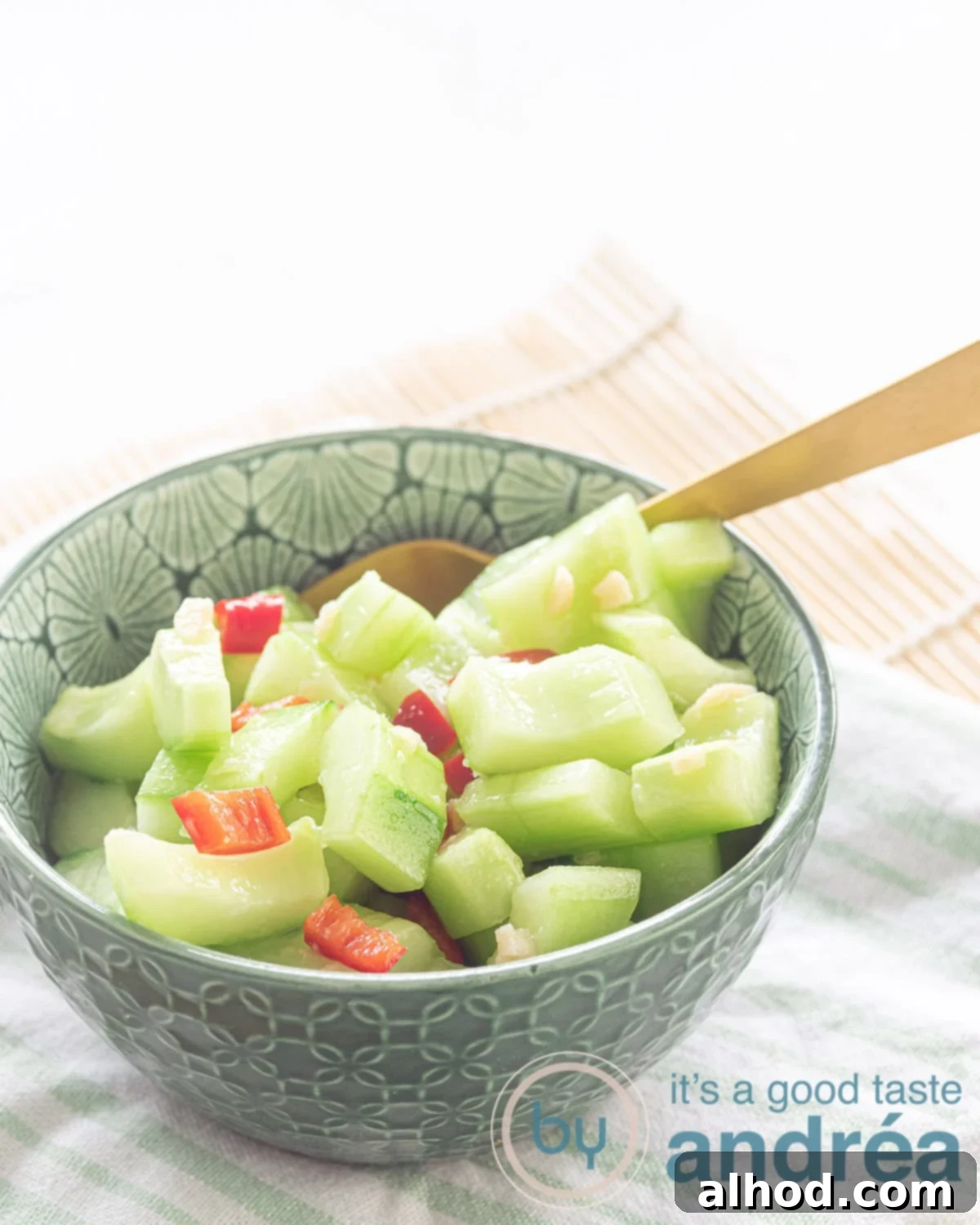 Zesty Garlic Pepper Cucumber Salad 3 A vibrant green bowl filled with sliced cucumber, red chili pepper, and minced garlic, glistening with a sweet and sour marinade, ready to be served.