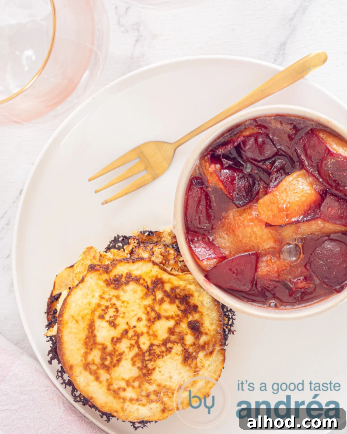 Fluffy Oatmeal Pancakes with Sweet Plum Compote 6 a white plate with oatmeal pancakes on the left and to the right plum compote. Above a golden fork. A white background.